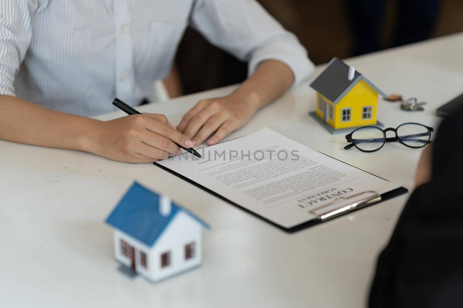 Businessman and estate agent signing a document for house deal by nateemee