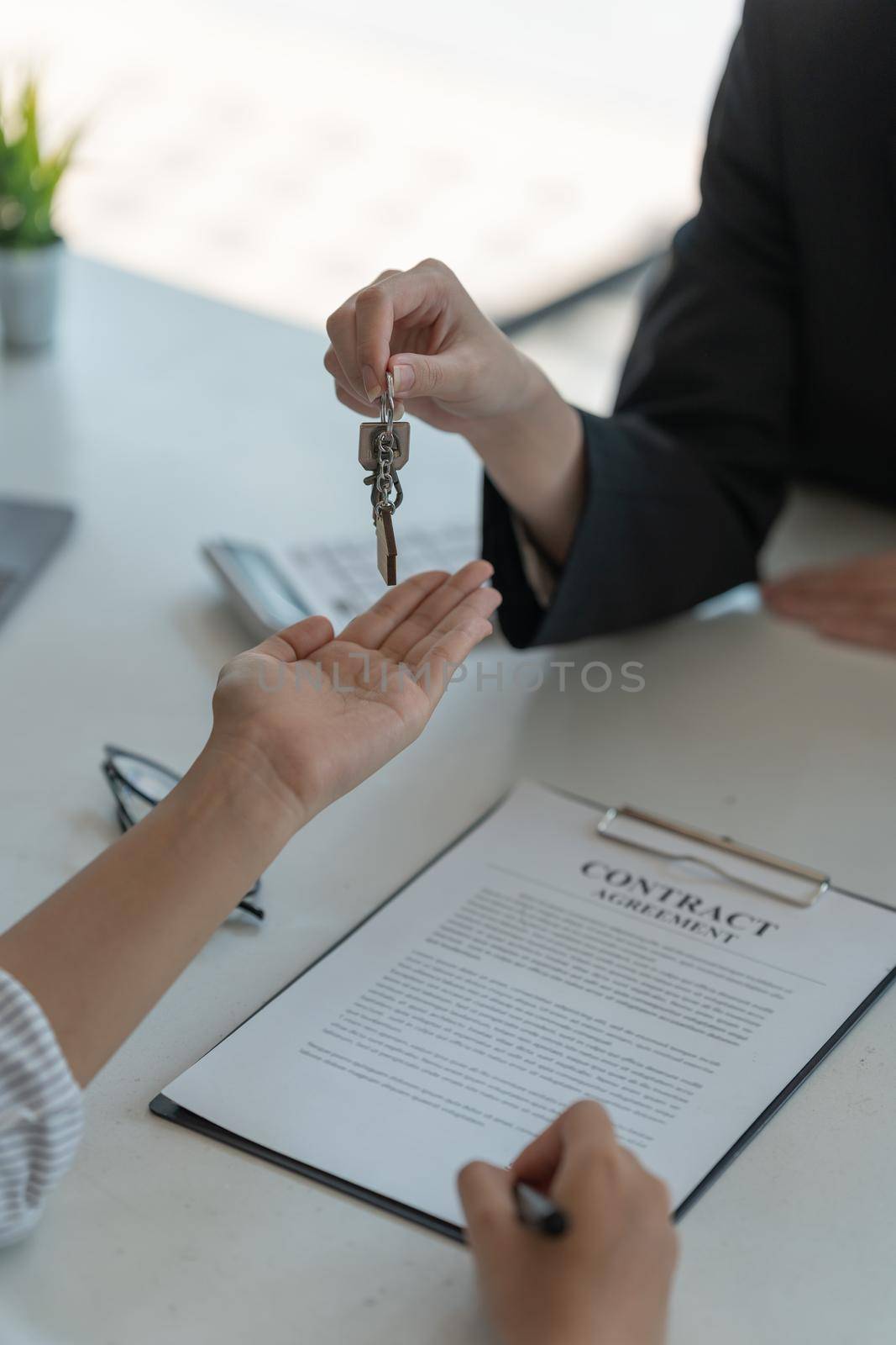 real estate agent holding house key to his client after signing contract agreement in office,concept for real estate, moving home or renting property by nateemee