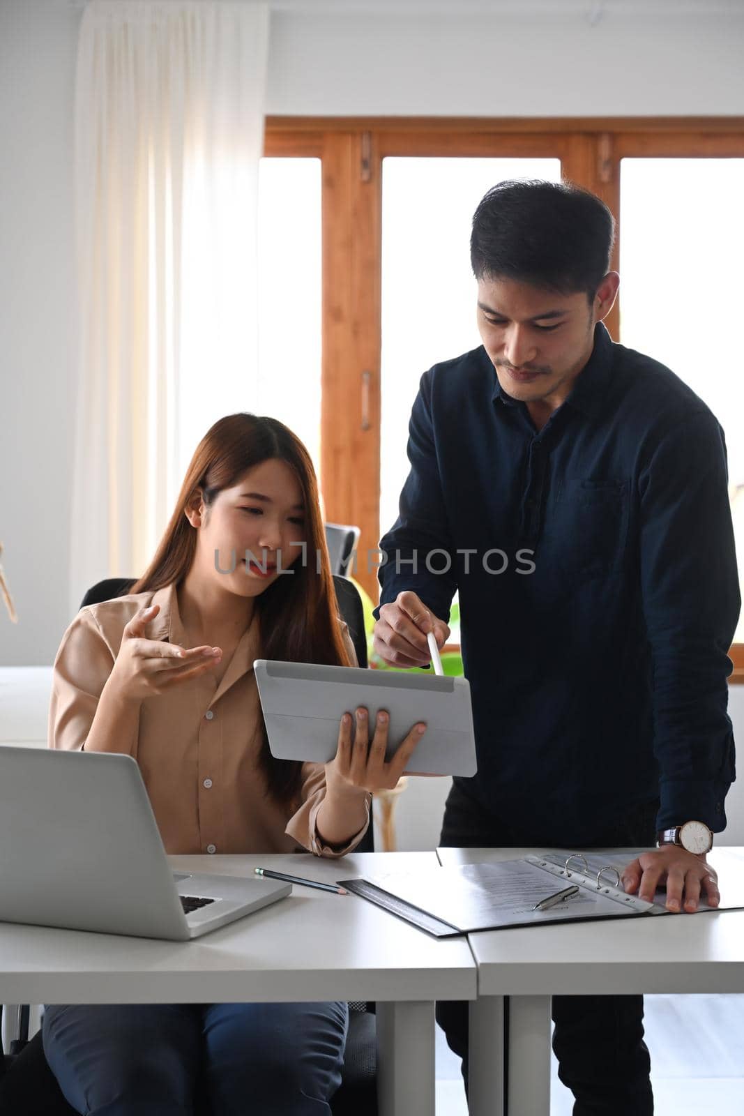 Beautiful businesswoman showing information on digital tablet to her male colleague.