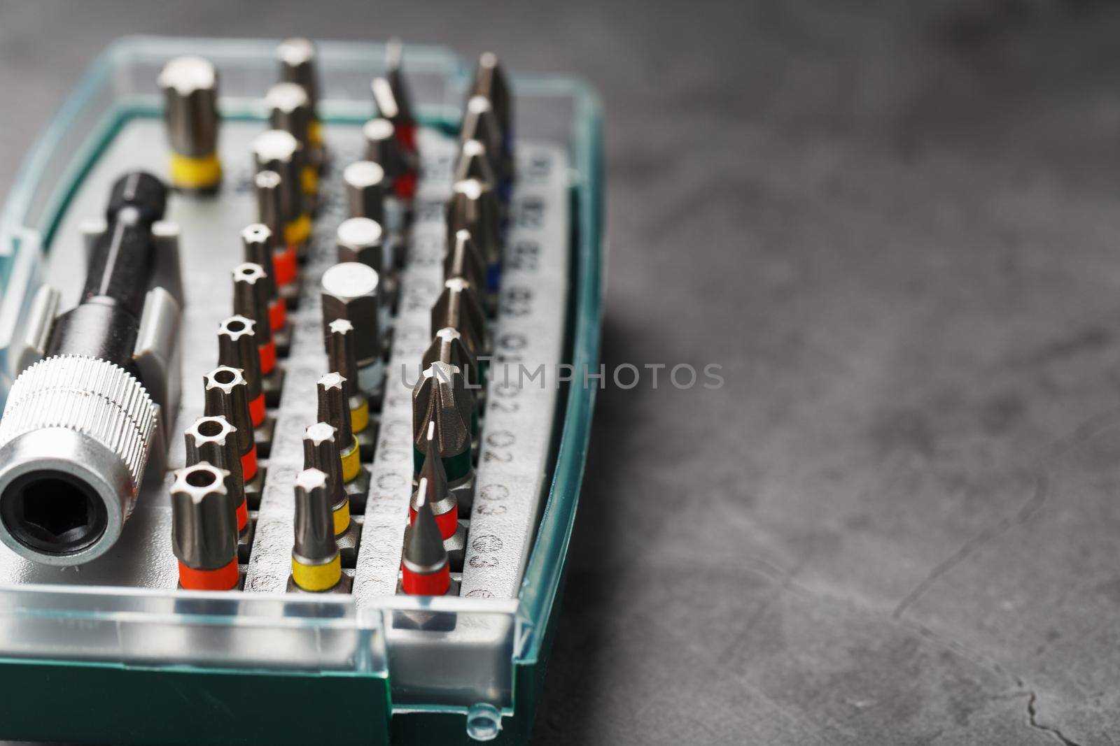 A set of different bits for screwdrivers and repairs in a box on a gray background by AlexGrec