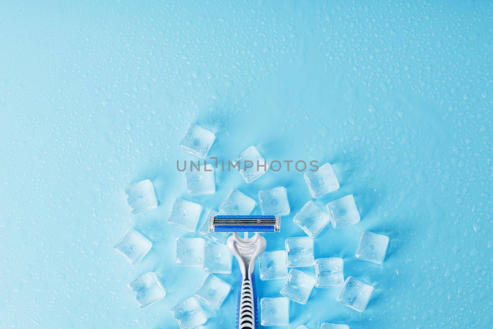 Blue shaving machines in a row on a blue background with ice cubes. The concept of cleanliness and frosty freshness