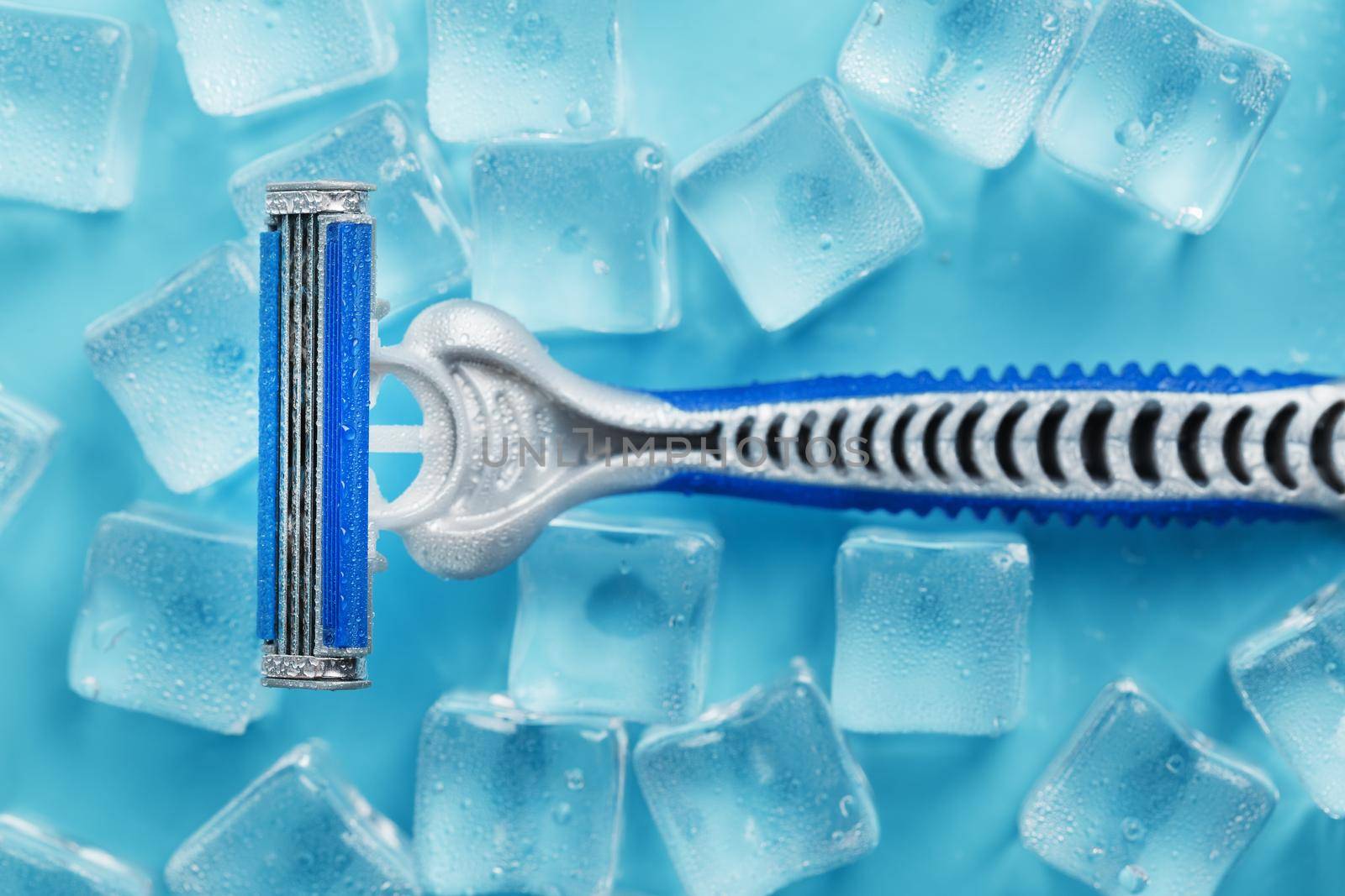 Shaving machine on a blue background with ice cubes. The concept of cleanliness and frosty freshness