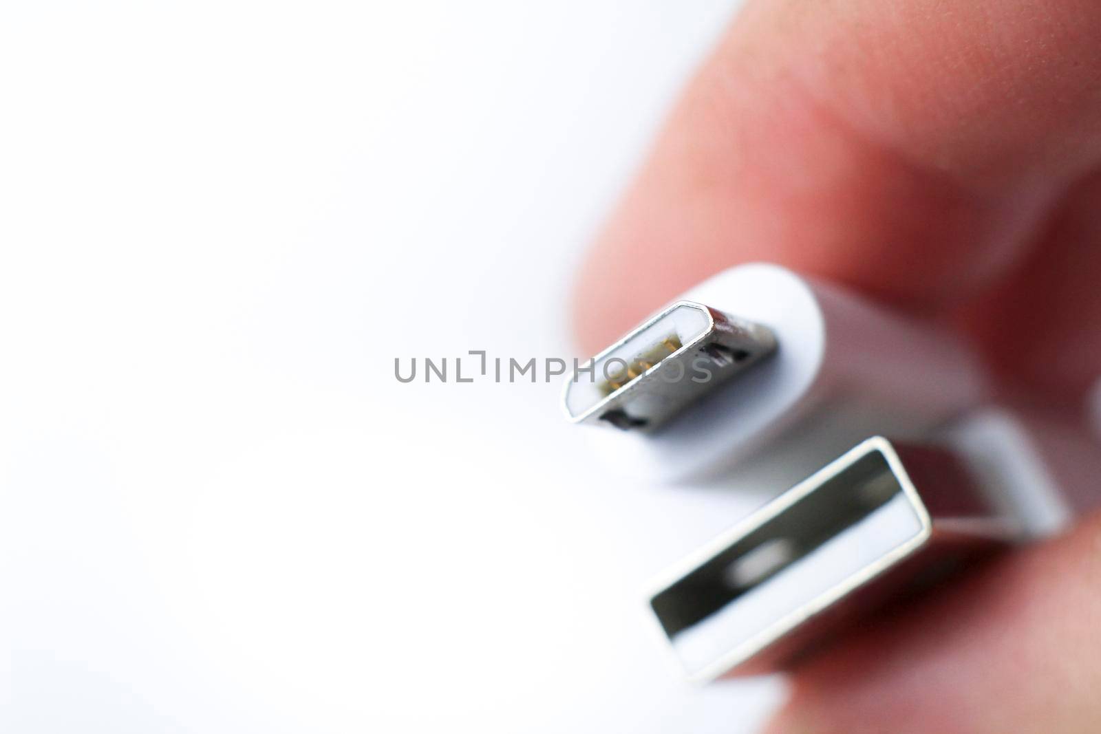 Hand holding micro USB cable connector on white background