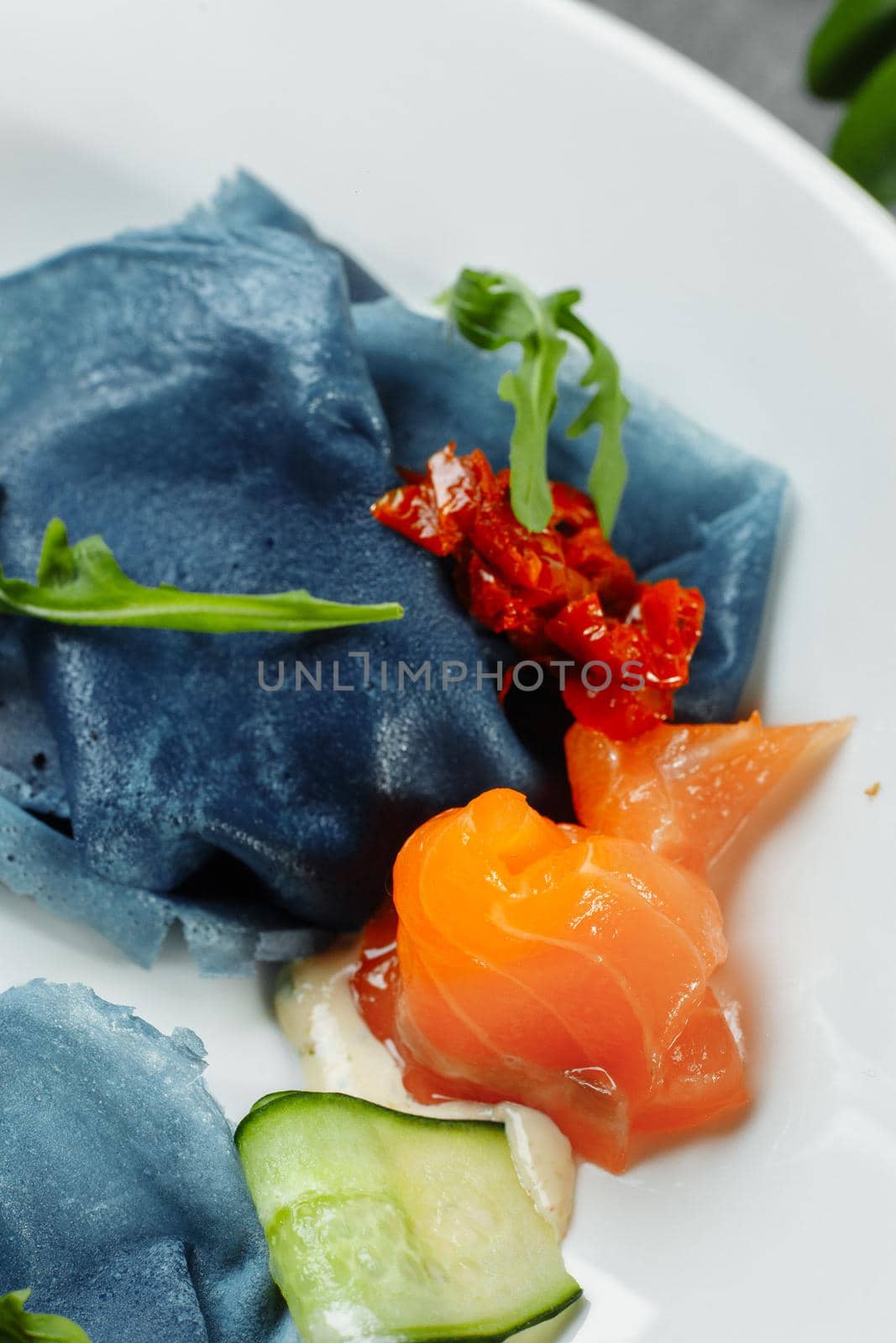 a stack of pancakes with salted salmon on a plate. Blue pancakes with salmon. Useful breakfast.