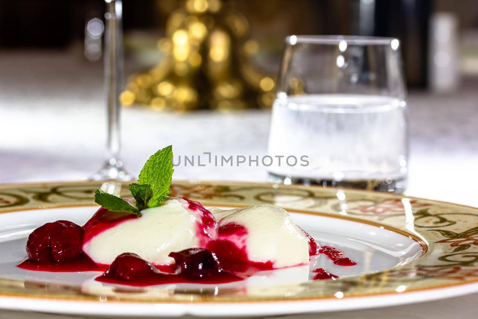 Panakota with cherry jelly and mint leaves on a white background by Milanchikov