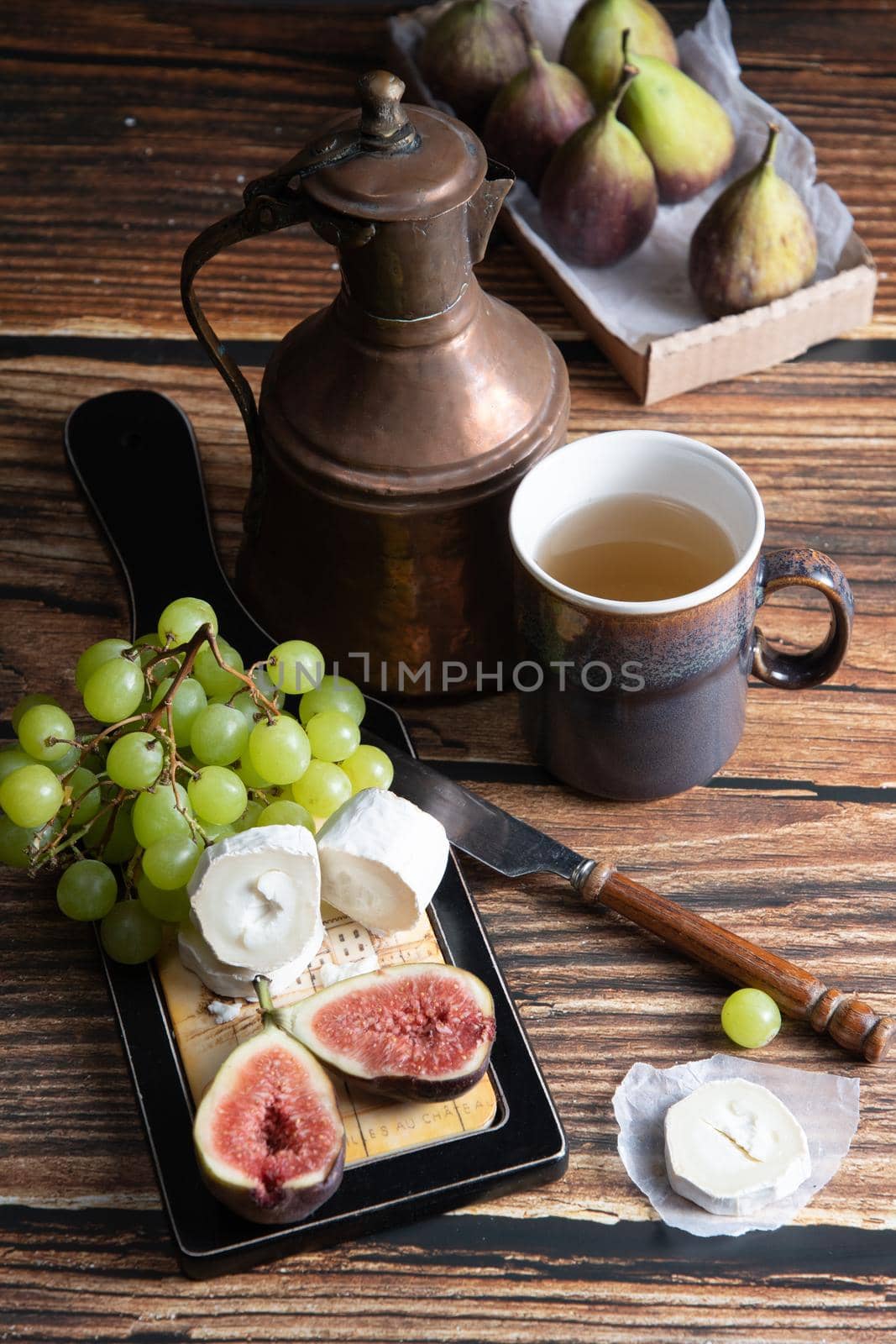 cheese plate with goat cheese, grapes and figs, copper teapot, angle view, healthy food, high-calorie breakfast. High quality photo