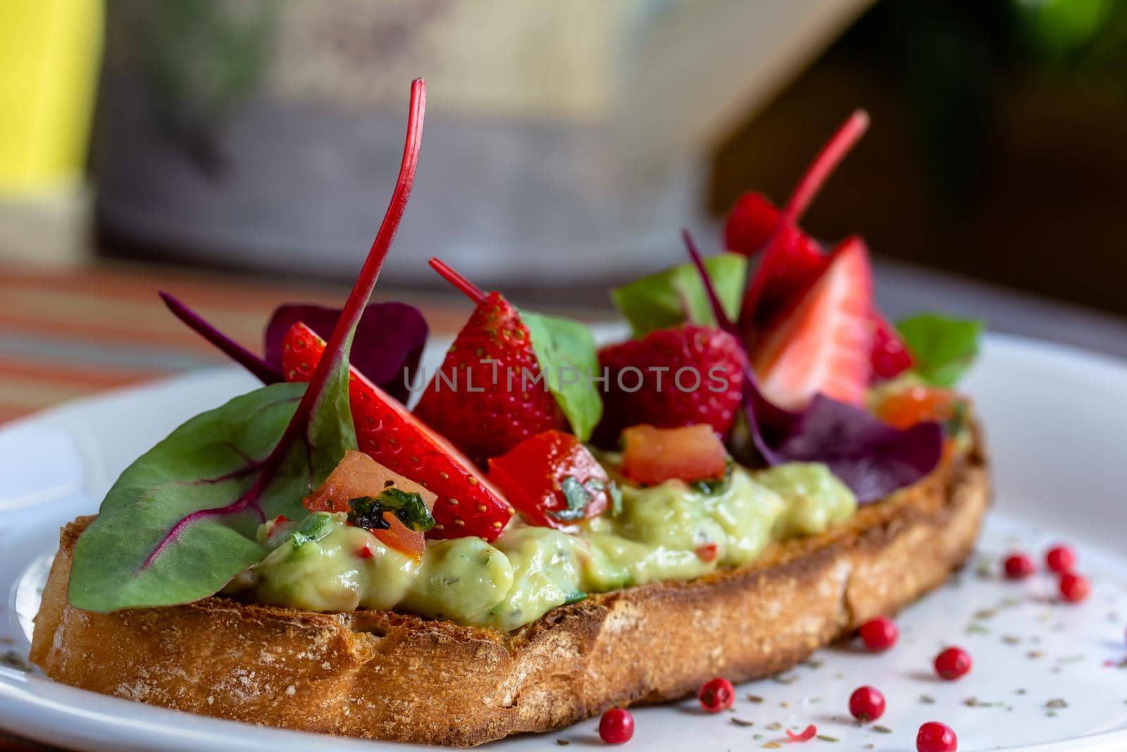 Keto diet avocado toast with strawberries, soft cheese, sesame seeds and herbs. healthy Breakfast or lunch. sandwich recipe mix media. top view, selective focus by Milanchikov