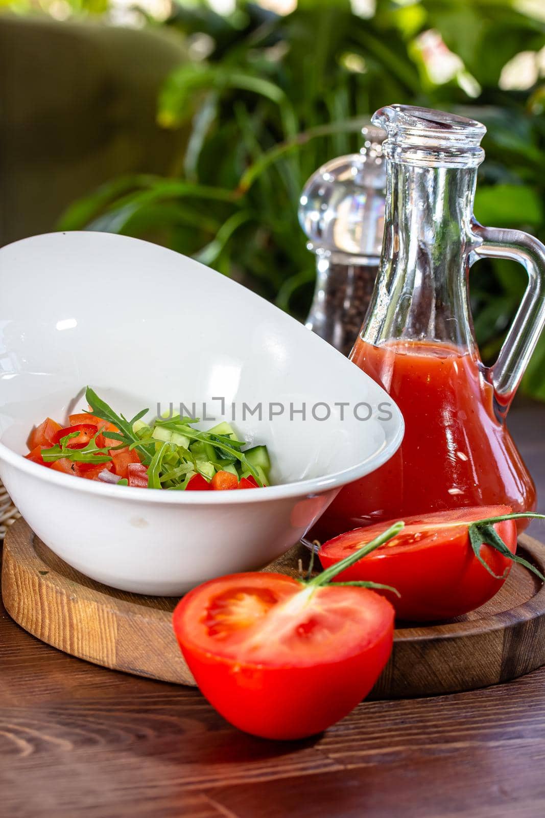 Tasty appetizing summer tomato soup puree gazpacho with tomatoes and cucumbers served in bowl on wooden background.