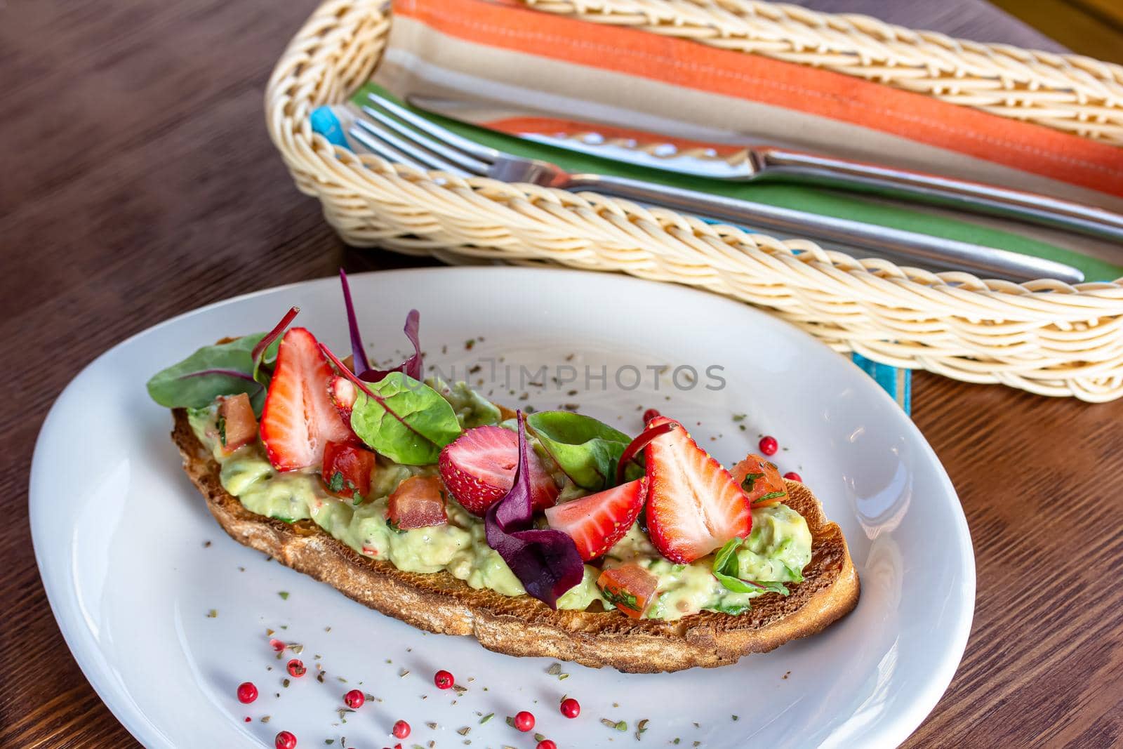 Keto diet avocado toast with strawberries, soft cheese, sesame seeds and herbs. healthy Breakfast or lunch. sandwich recipe mix media. top view, selective focus by Milanchikov