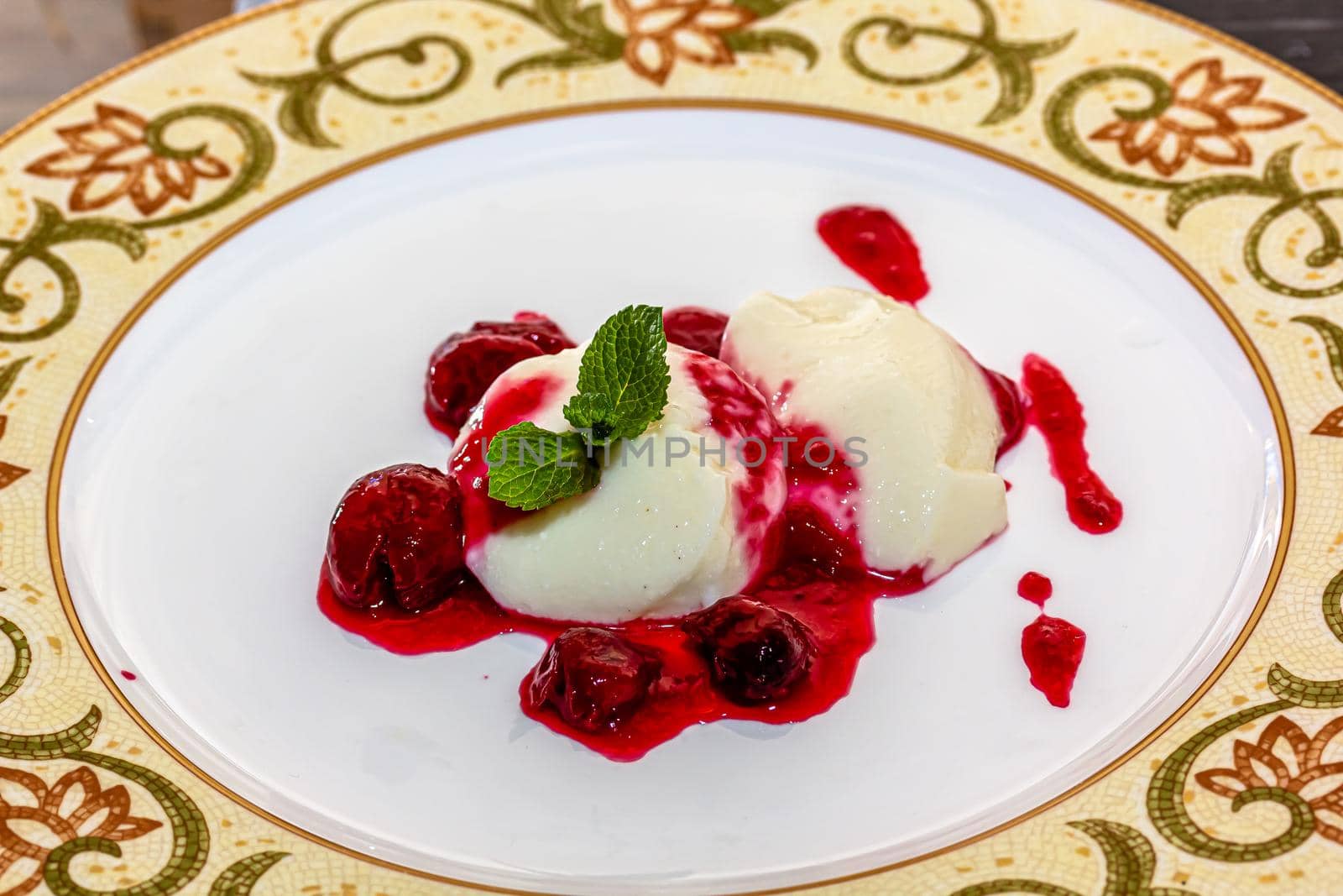 Panakota with cherry jelly and mint leaves on a white background.