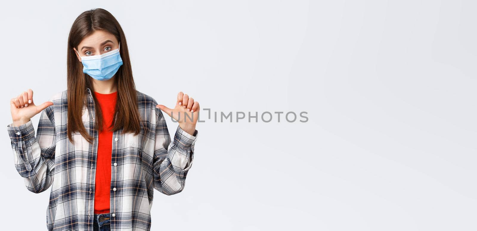 Coronavirus outbreak, leisure on quarantine, social distancing and emotions concept. Confident young woman in medical mask, freelancer pointing herself, show-off or bragging personal achievement.