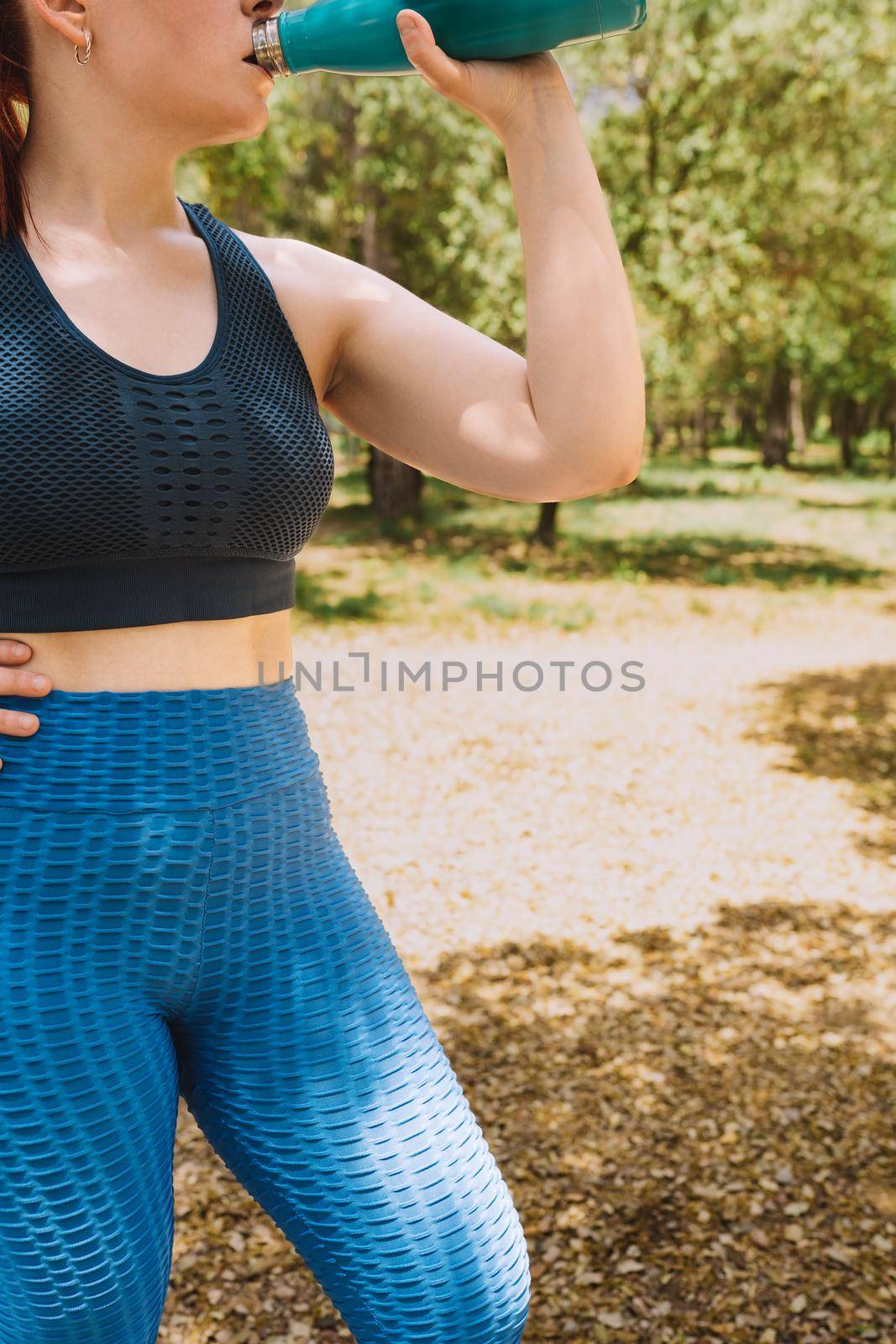 cropped shot of a young fitness woman drinking water to refresh herself from a bottle after a sports workout. girl practising sport outdoors. health and wellness lifestyle. vertical by CatPhotography