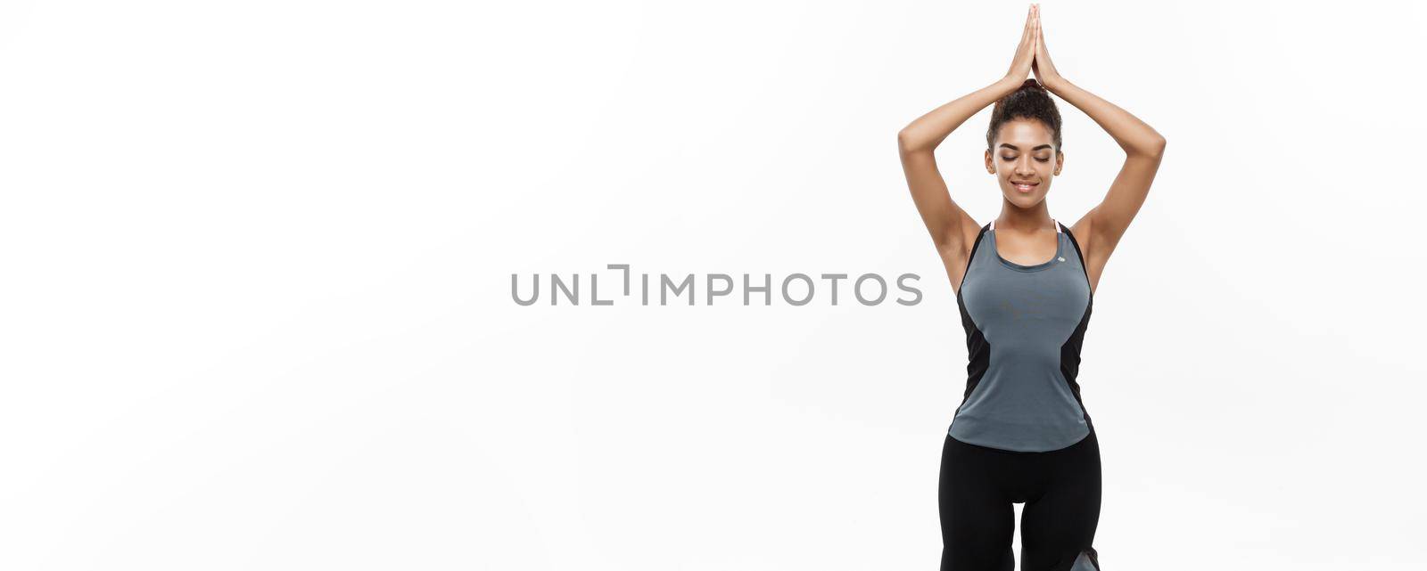 Healthy and Fitness concept - Beautiful American African lady in fitness clothing doing yoga and meditation. Isolated on white background. by Benzoix