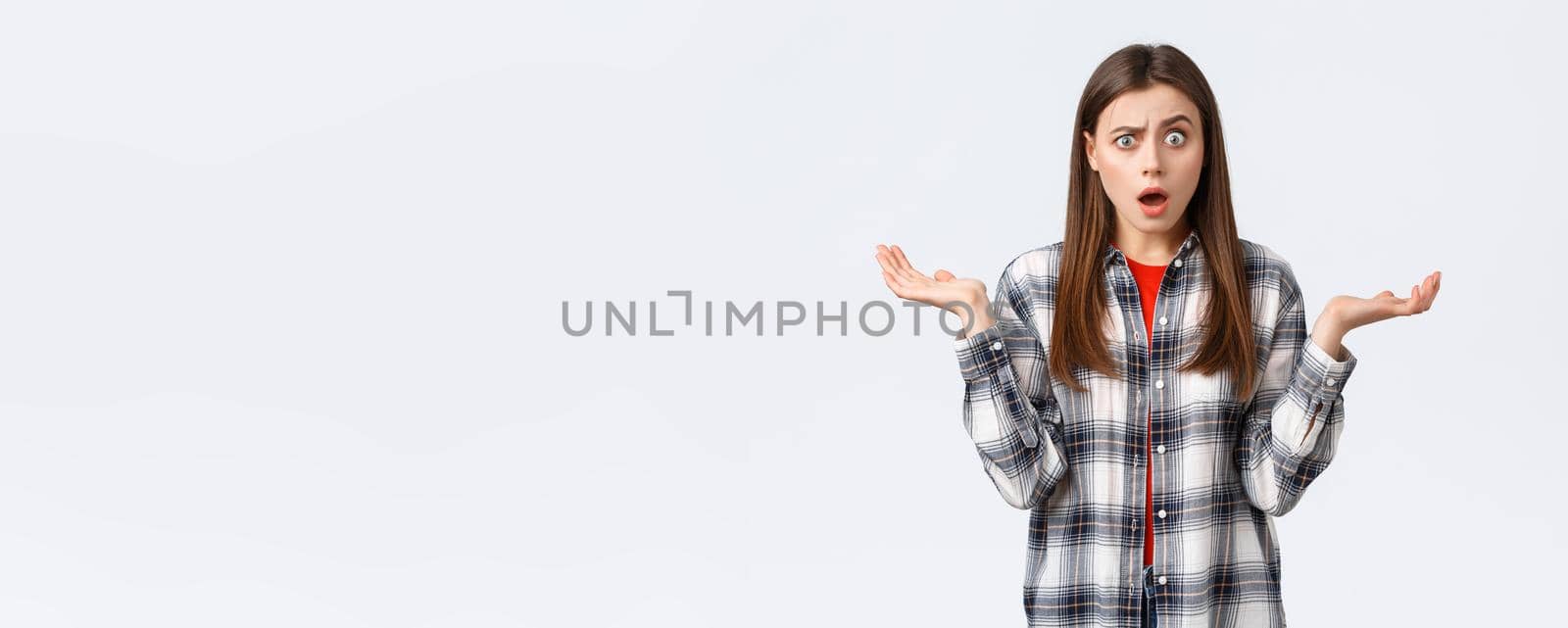 Lifestyle, different emotions, leisure activities concept. Confused and surprised young woman gasping, drop jaw and stare startled from big news, spread hands sideways, unexpected situation.
