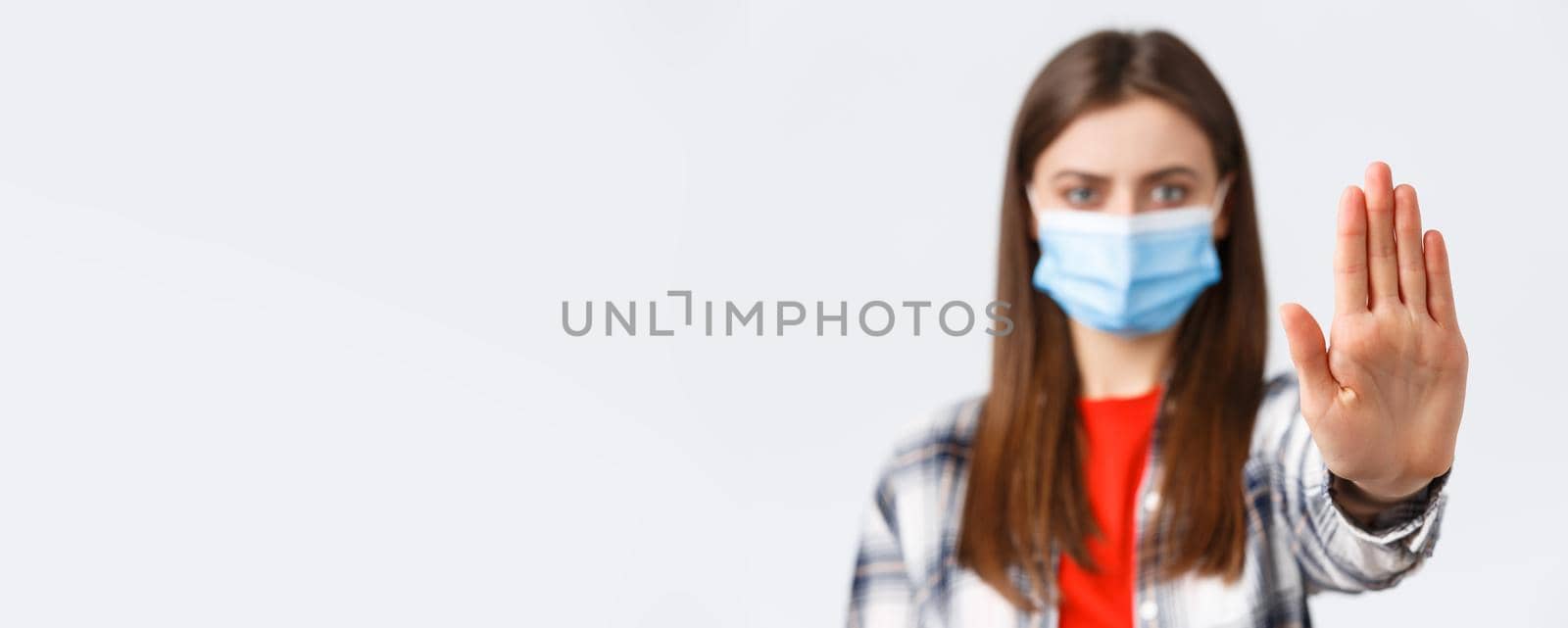 Coronavirus outbreak, leisure on quarantine, social distancing and emotions concept. Close-up of serious woman stretch palm to say stop, restrict or prohibit from bad decisions, wear medical mask by Benzoix