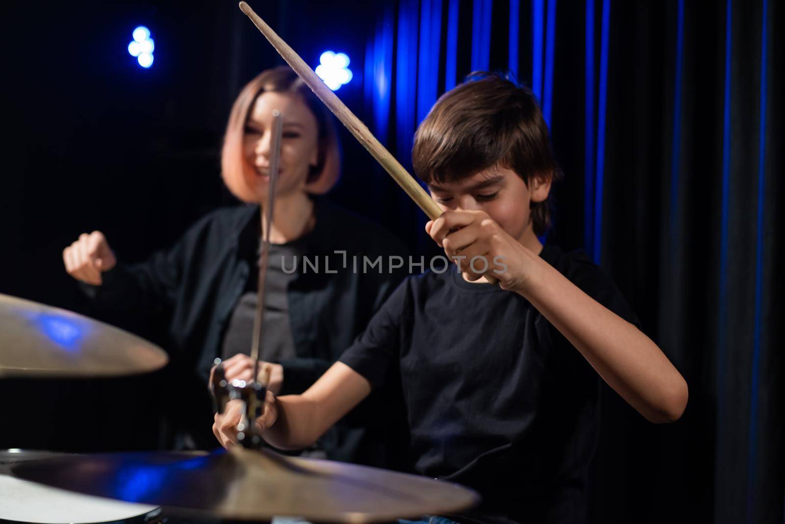 Young woman teaching boy to play drums