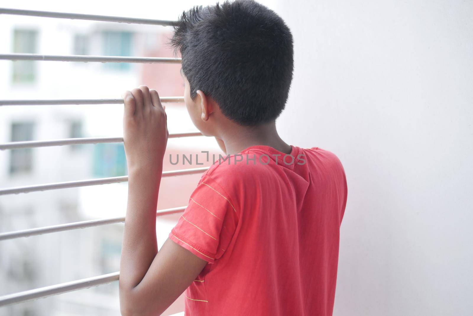 sad teenage boy looking through window .