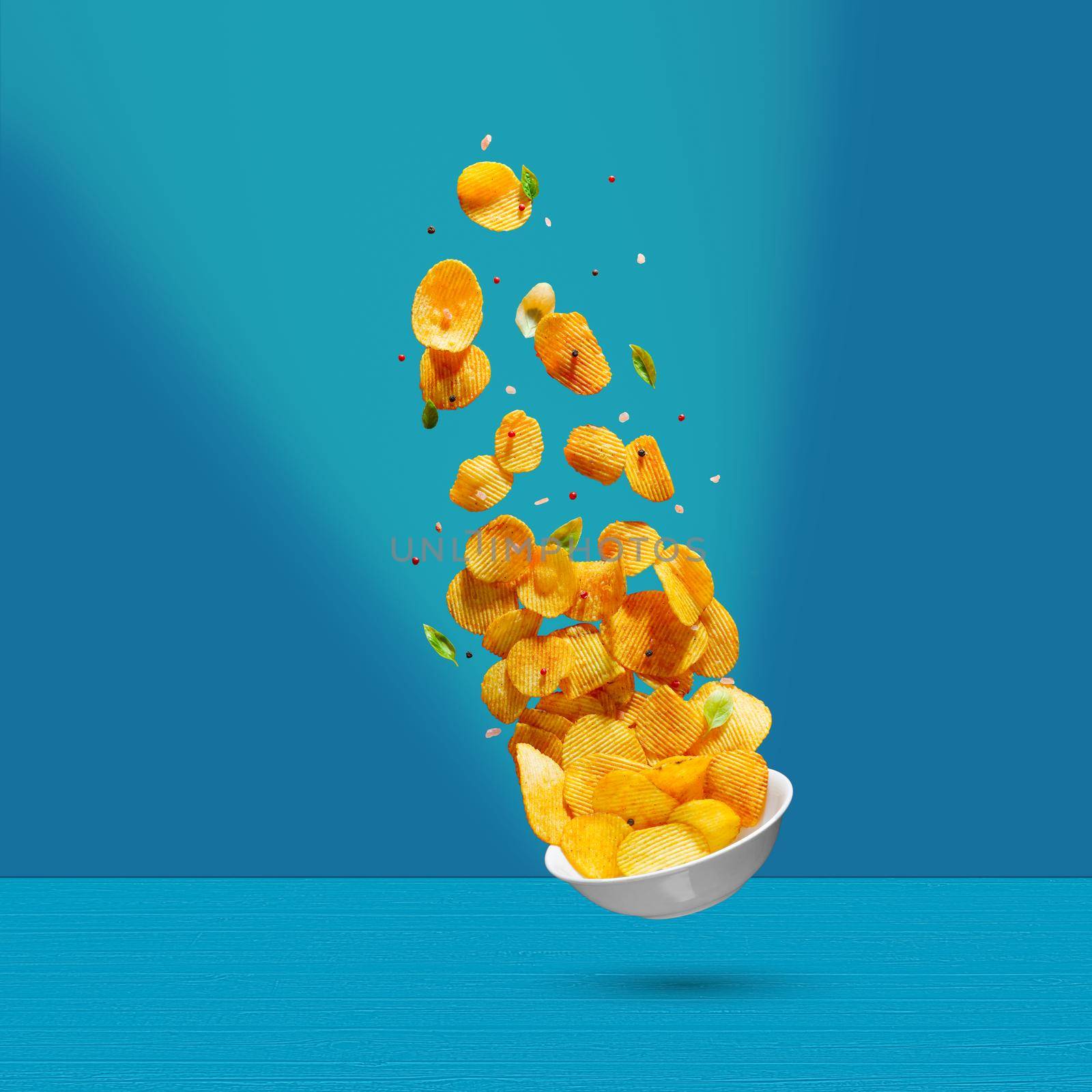 Potato chips falling onto plate on white background. Advertising concept. Levitation flying chips by PhotoTime