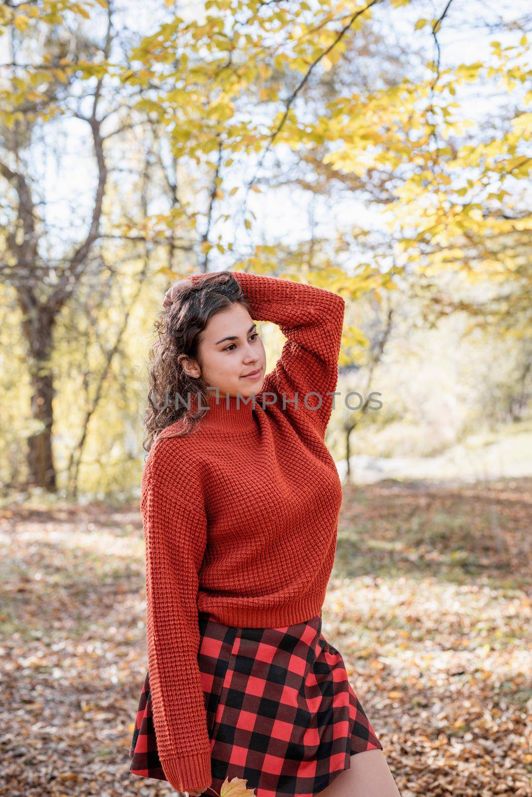 Autumn nature. young happy woman in red sweater and skirt walking in autumn forest