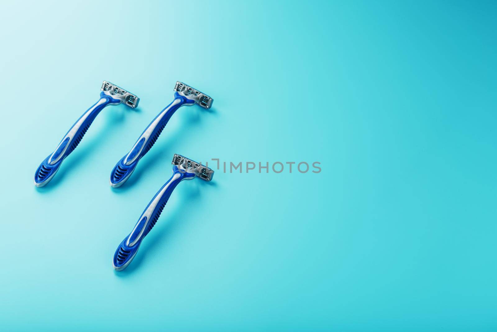 Three shaving machines on a blue background with free space, top view