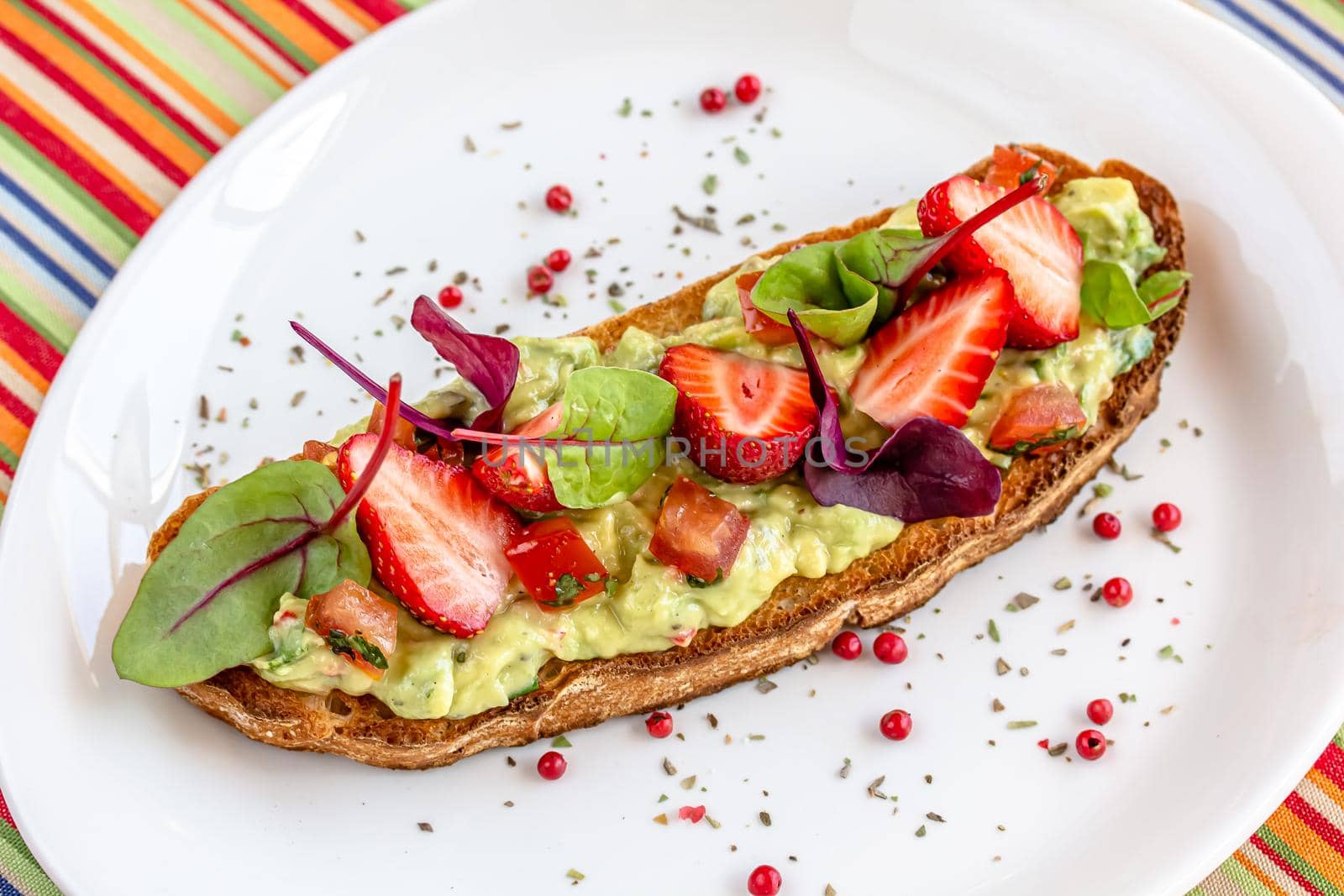Keto diet avocado toast with strawberries, soft cheese, sesame seeds and herbs. healthy Breakfast or lunch. sandwich recipe mix media. top view, selective focus by Milanchikov