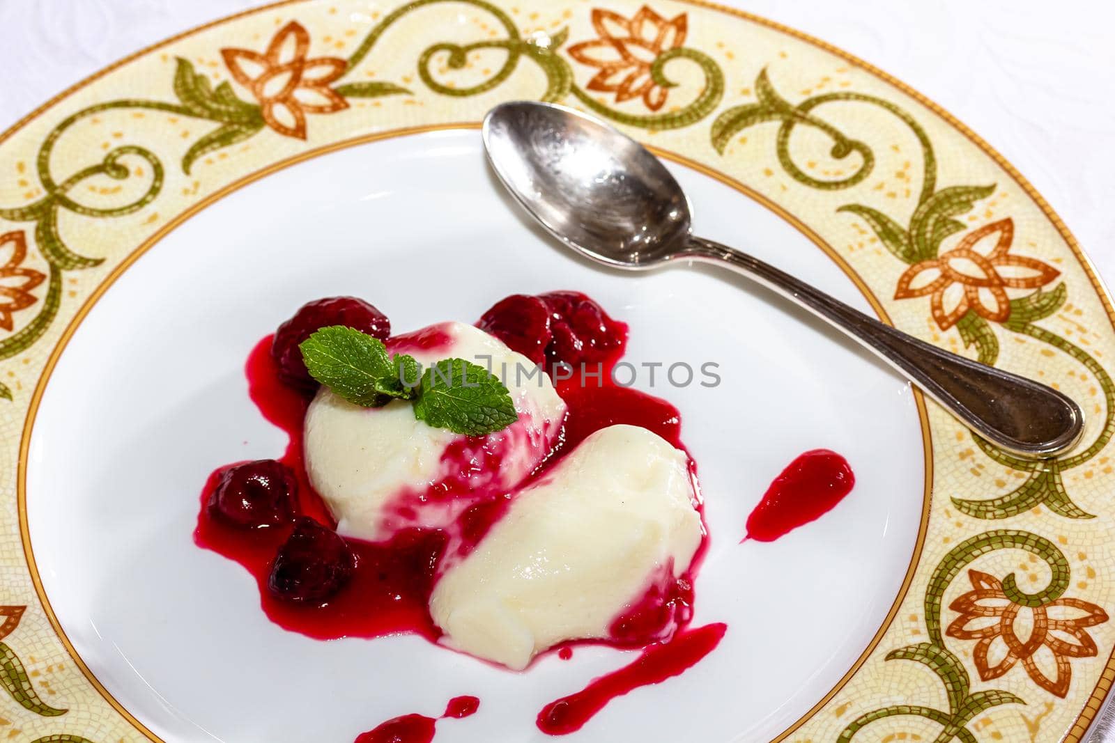 Panakota with cherry jelly and mint leaves on a white background by Milanchikov