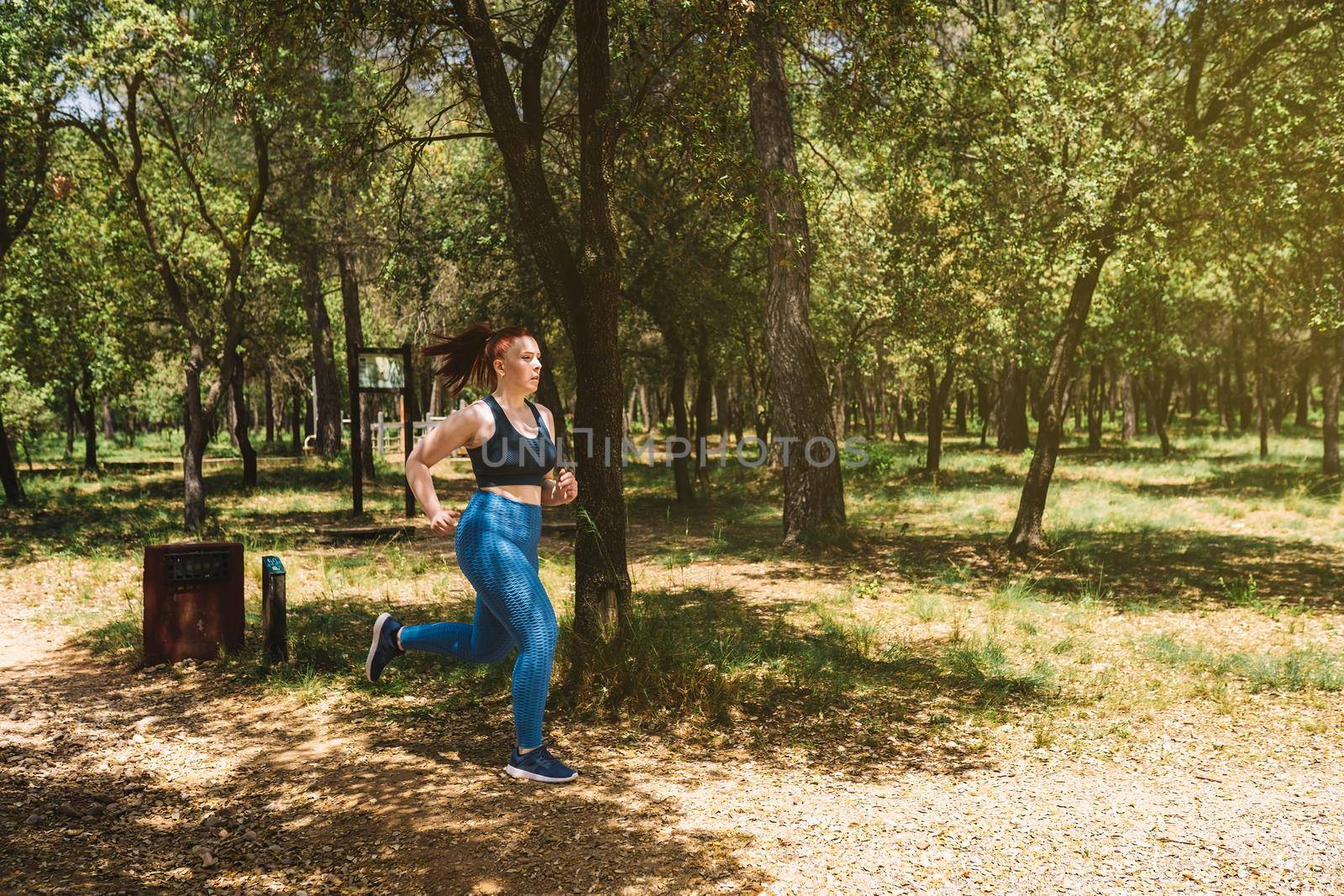 young woman athlete training, running in nature to tone the body. athlete practising outdoor sport. health and wellness lifestyle. by CatPhotography