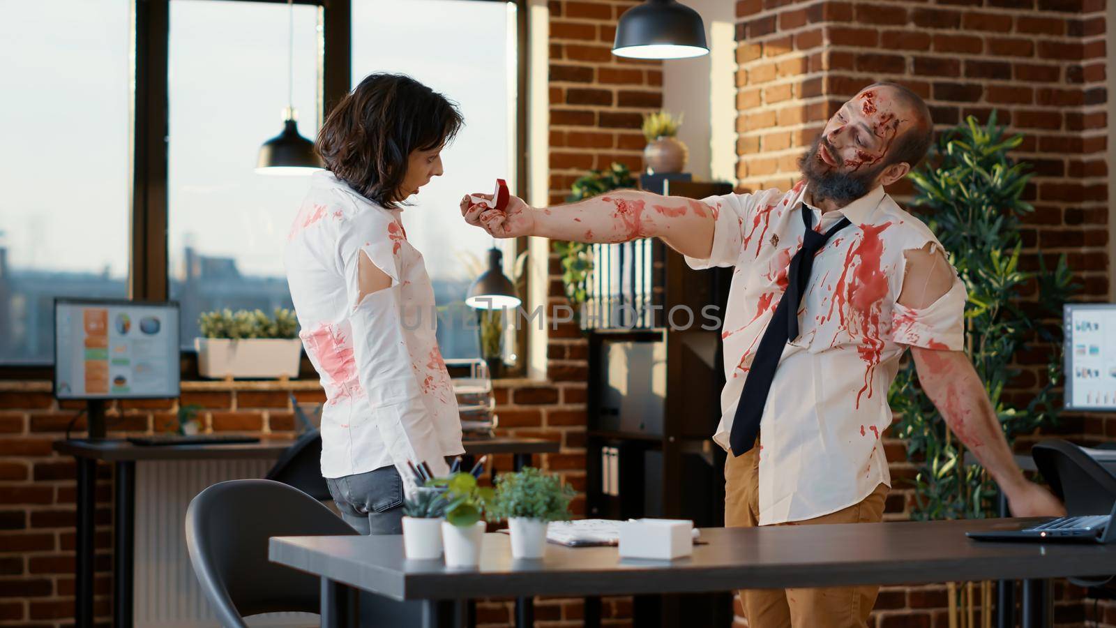 In love dead walking couple getting married inside company workspace. Bizarre looking undead evil monster with deep and bloody wounds and scars in office proposing his girlfriend.