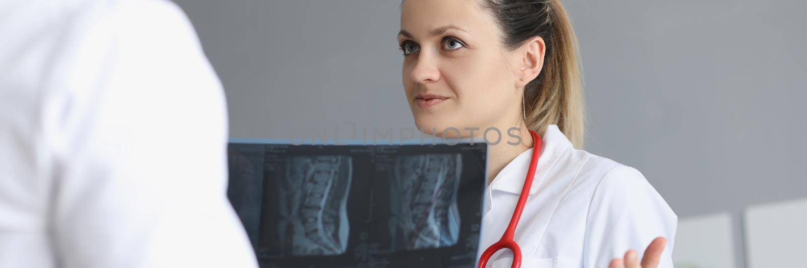 Portrait of female doctor deliberate with colleague about patients medical history. Worker hold scan result of clients checkup. Medicine, treatment concept