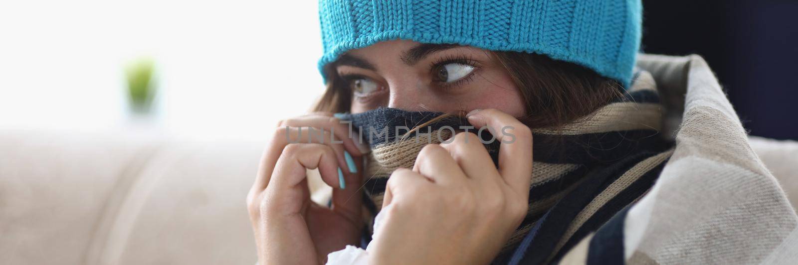 Portrait of young woman hide nose in scarf feeling cold because of high temperature. Girl get care at home, stay on self isolation. Covid, health concept