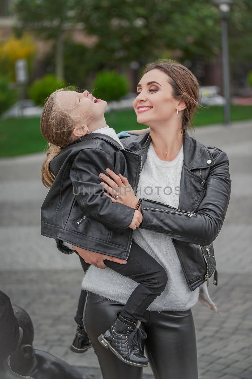 Mom carries her daughter in her arms while walking in the city