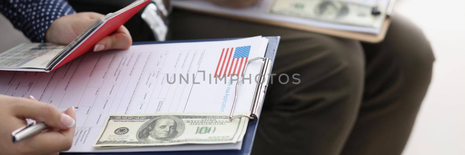 Close-up of men sit in line and filling visa application forms to get access to enter country. Boring process with docs at consulate. International concept