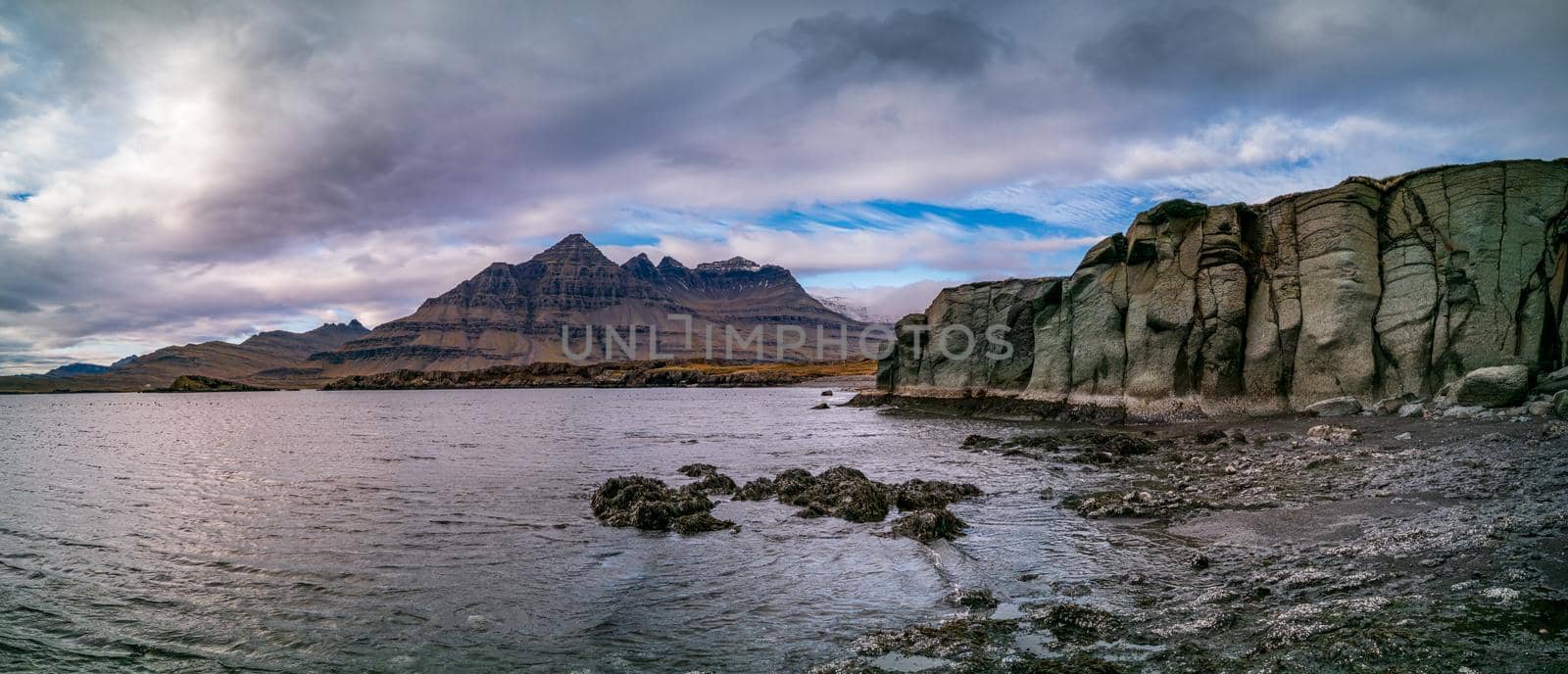 Green rock, fjord and mountain peaks panorama in Iceland
