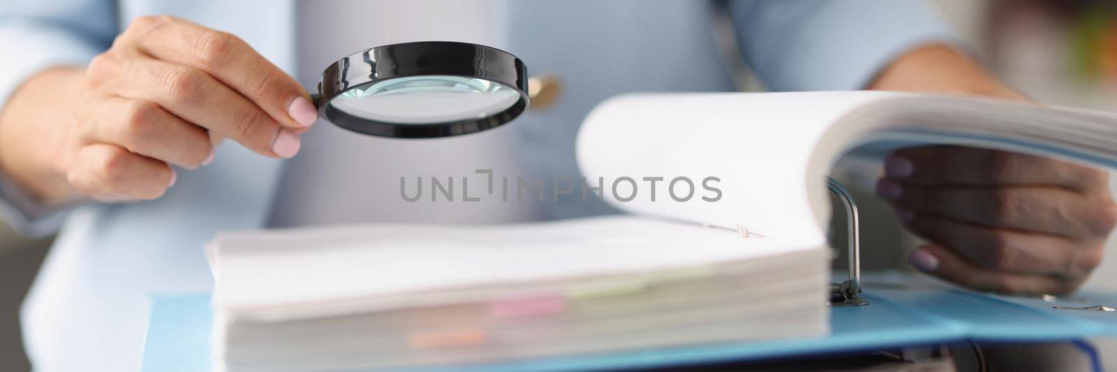 Businesswoman looking through magnifying glass tool on documents by kuprevich