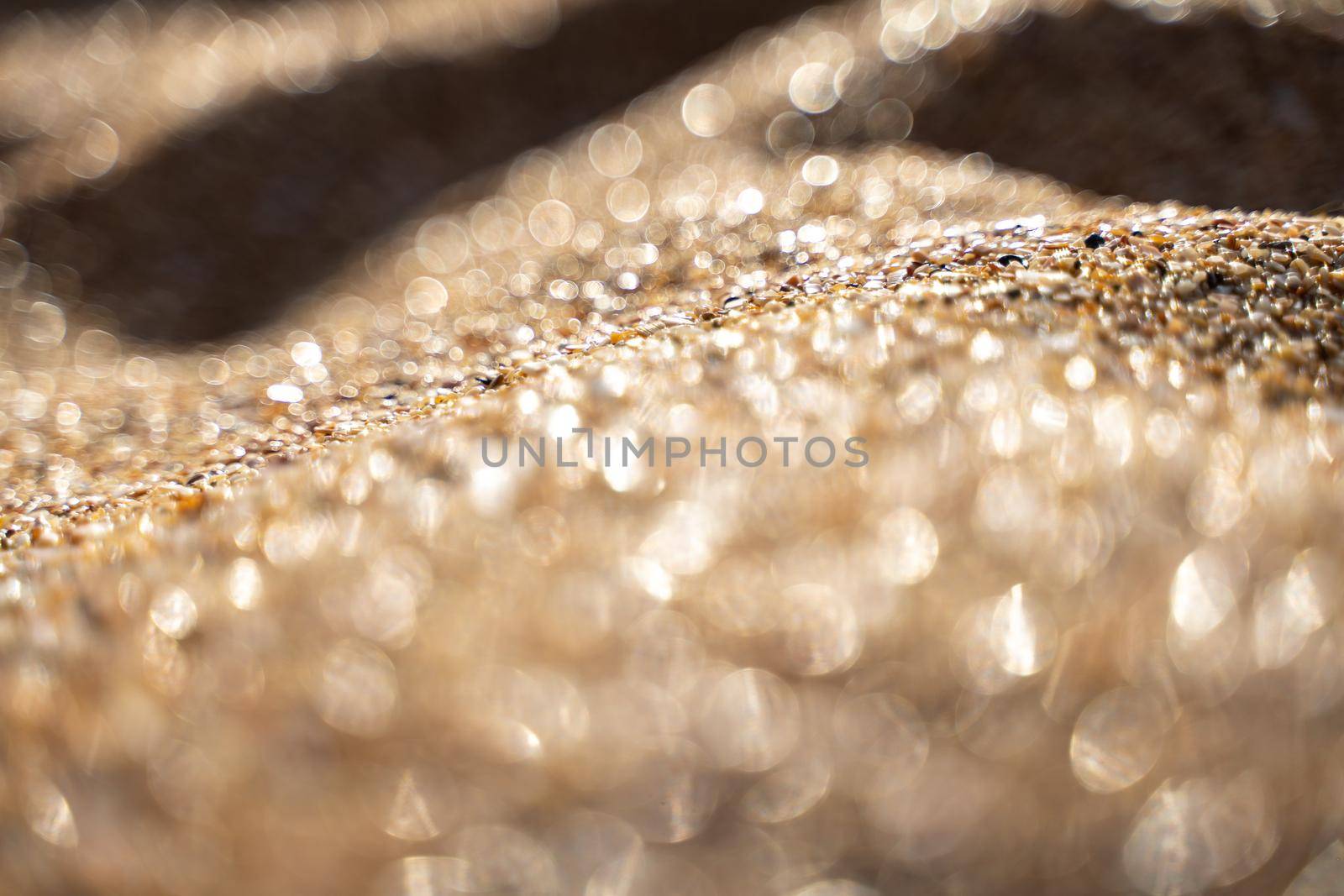 Golden sand on the coast at sunset with bokeh.