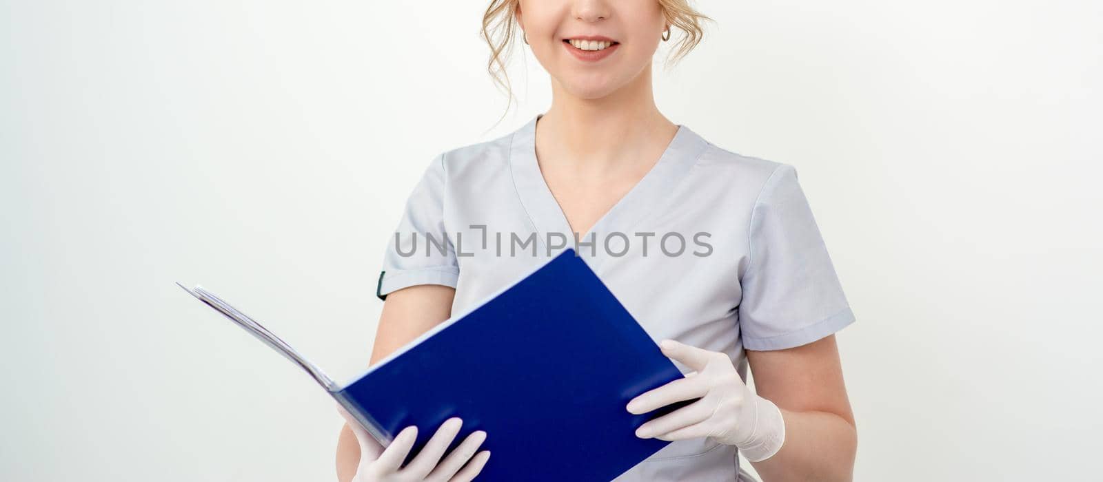 Portrait of pretty young caucasian student holding blue folder looking at camera on white background