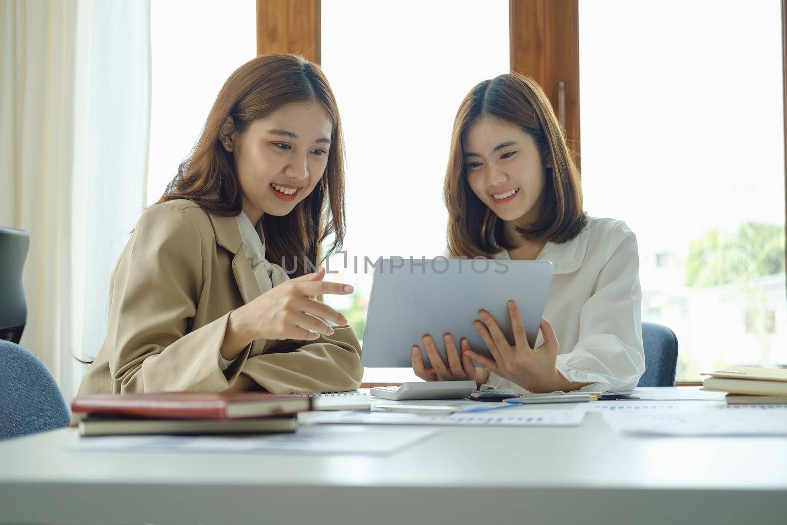 Negotiation, Analysis, Discussion, Portrait of an Asian women economist and marketer using tablet computer to plan investments and financial to prevent risks and losses for the company by Manastrong