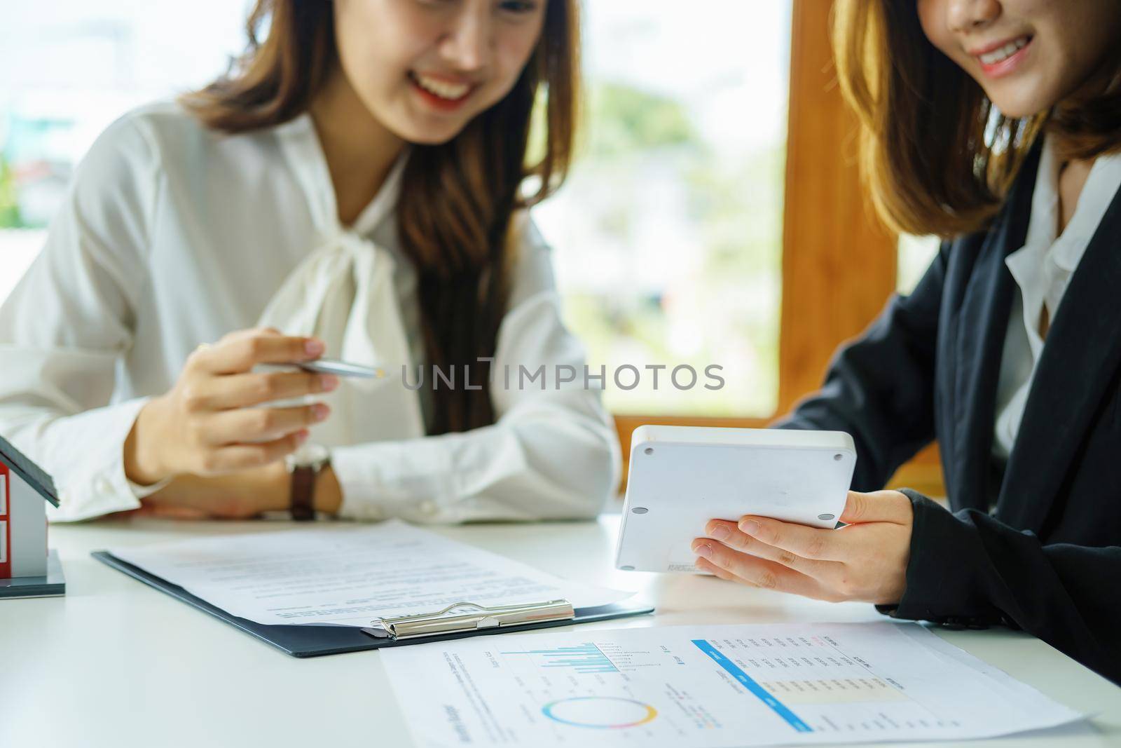 Guarantee, mortgage, contract, contract, signed, real estate agent or bank officer holding a calculator, submits a bid with a customer to buy a home before signing to make a deal by Manastrong