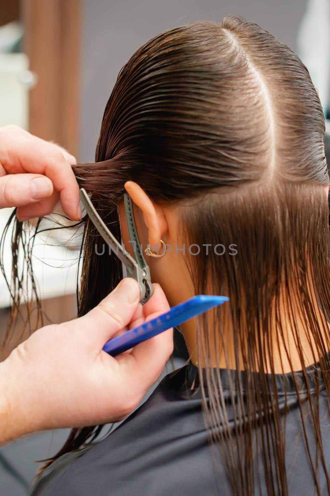 Hands of hairdresser combs hair of young woman in hair salon. Hairstyle process in a beauty salon