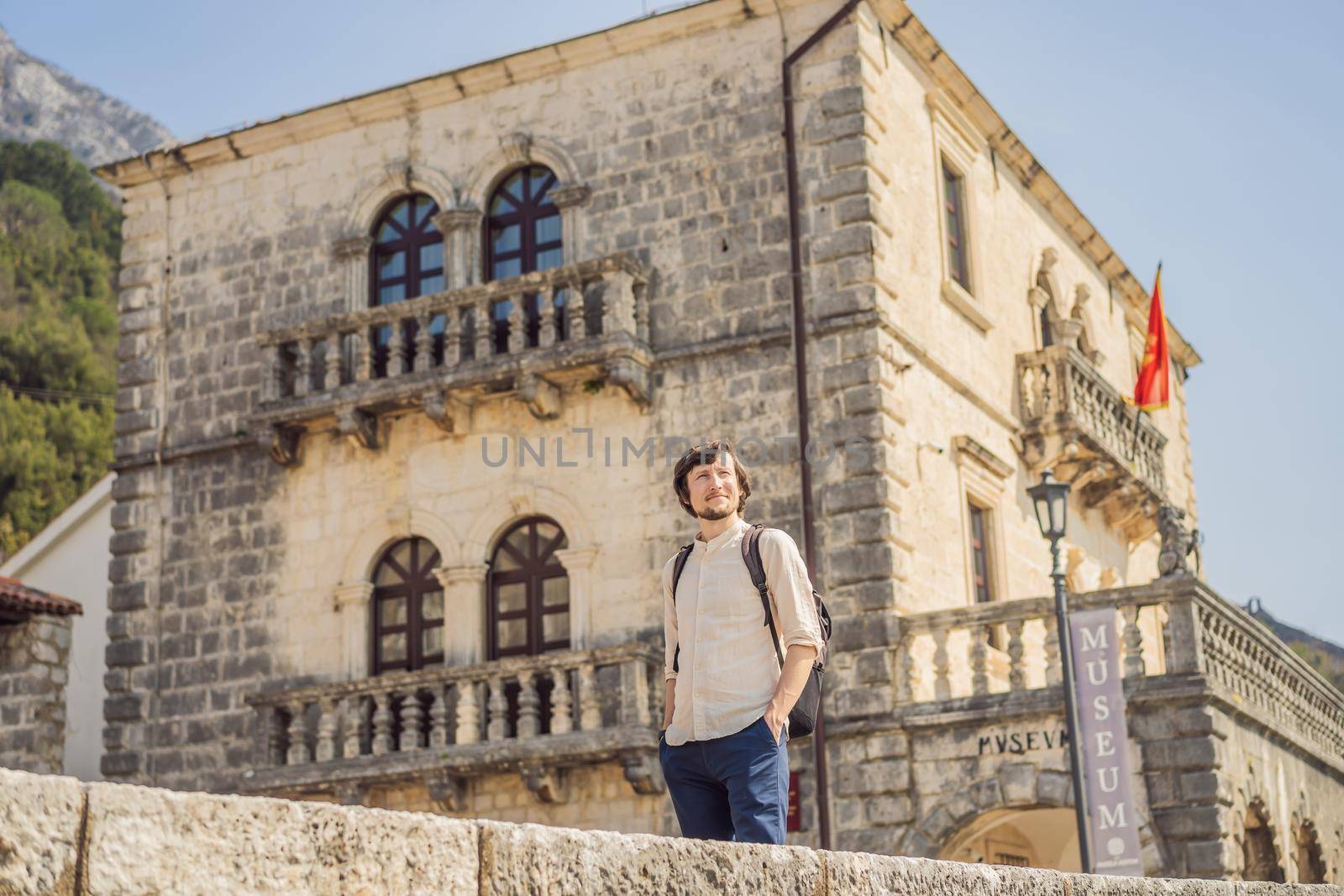 Man tourist enjoying Colorful street in Old town of Perast on a sunny day, Montenegro. Travel to Montenegro concept. Scenic panorama view of the historic town of Perast at famous Bay of Kotor on a beautiful sunny day with blue sky and clouds in summer, Montenegro, southern Europe by galitskaya