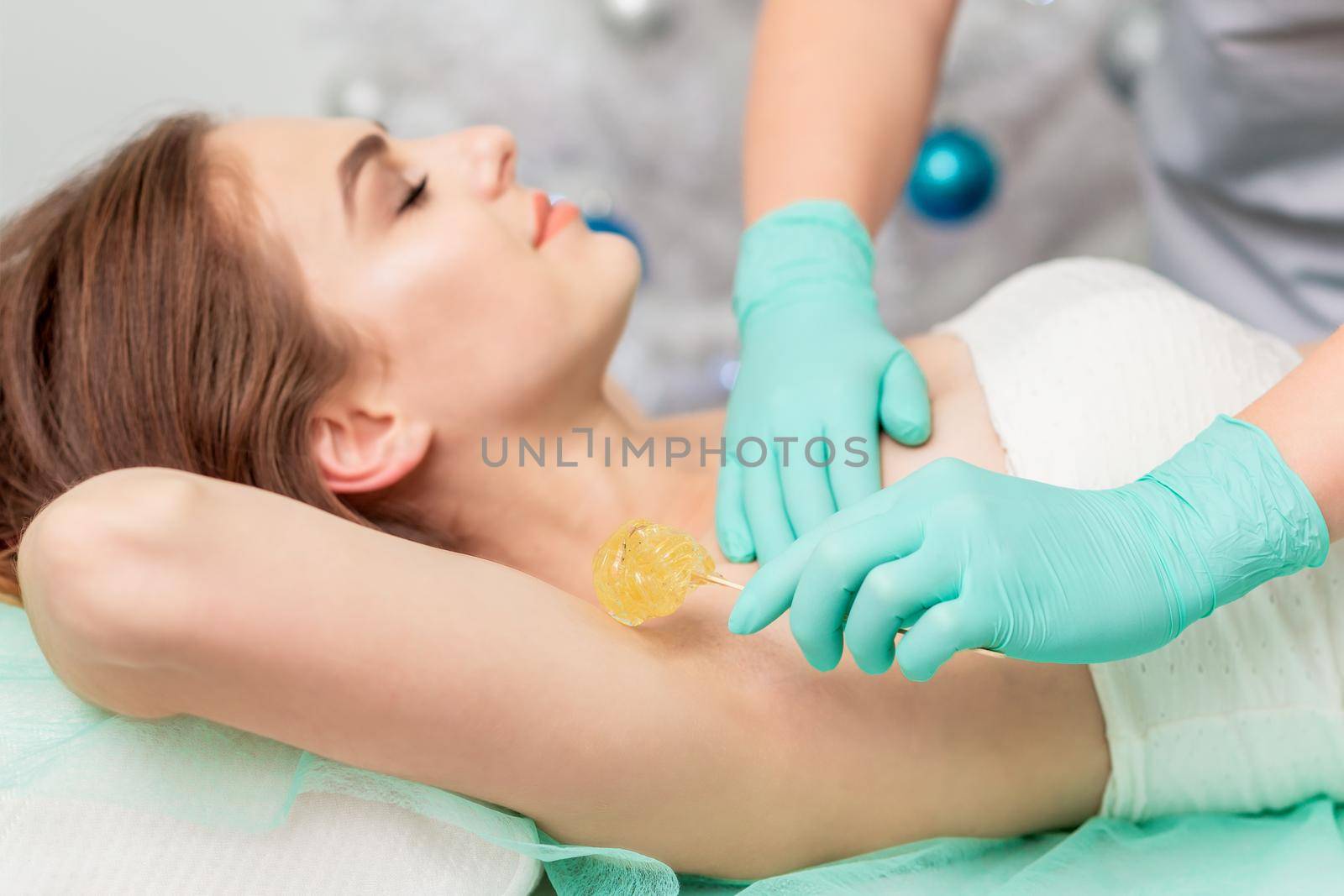 Epilation armpit of young woman by beautician close up.