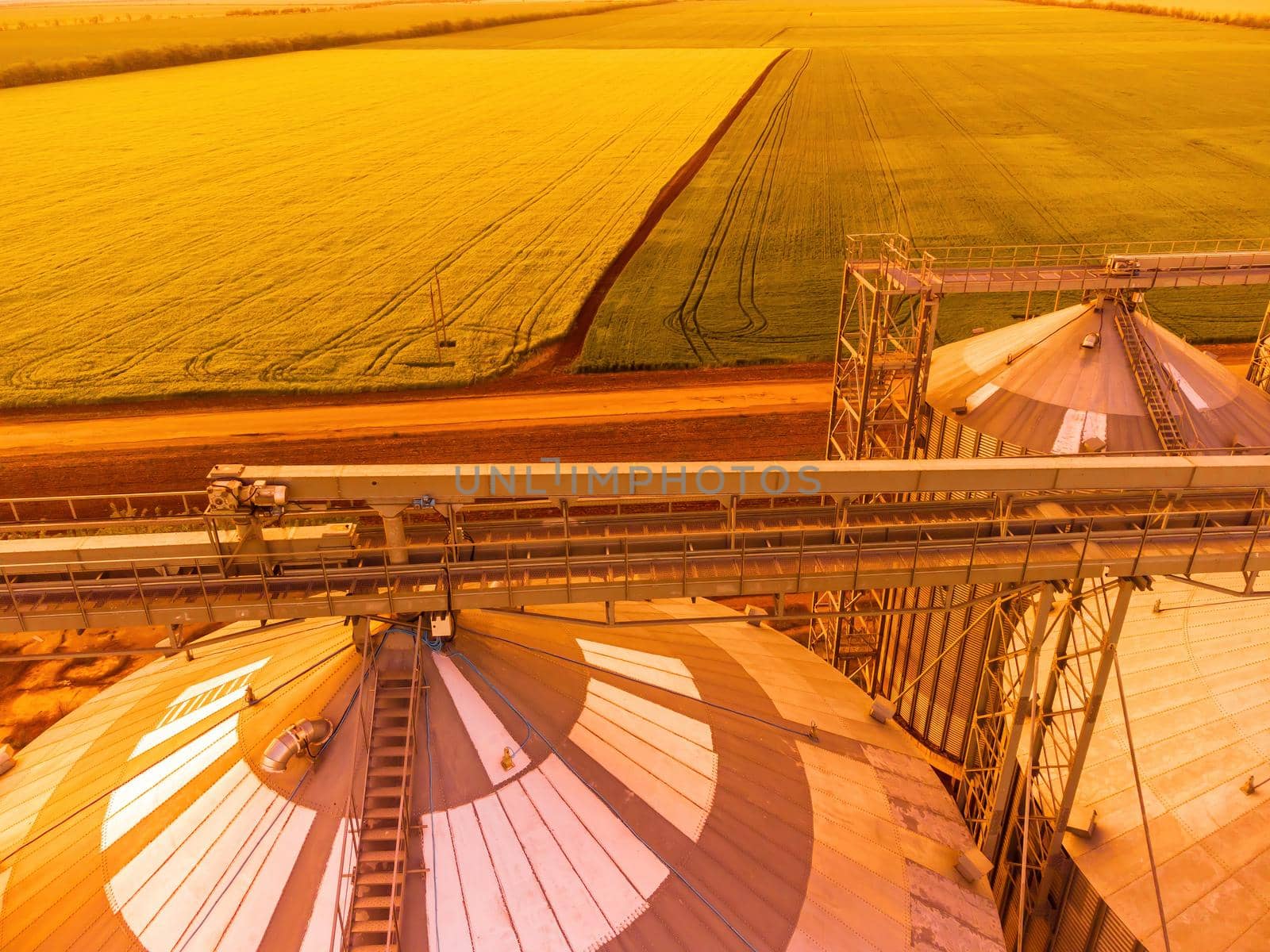 Grain elevator. Metal grain elevator in agricultural zone. Agriculture storage for harvest. Grain silos on green nature background. Exterior of agricultural factory