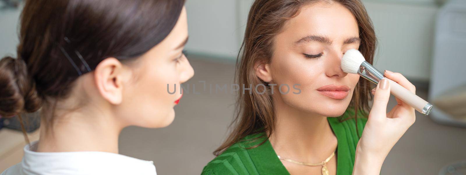 Makeup artist applying dry cosmetic tonal foundation on nose by okskukuruza