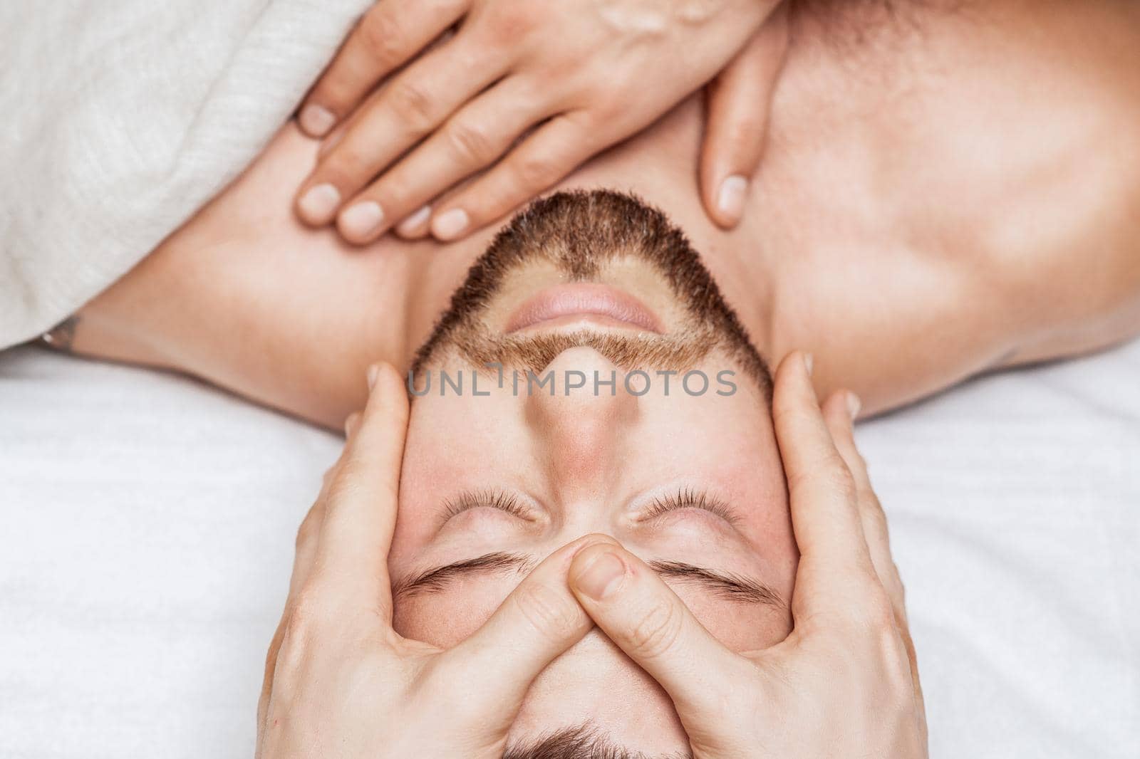 Man receiving relaxing head massage by massage therapist hands, top view.