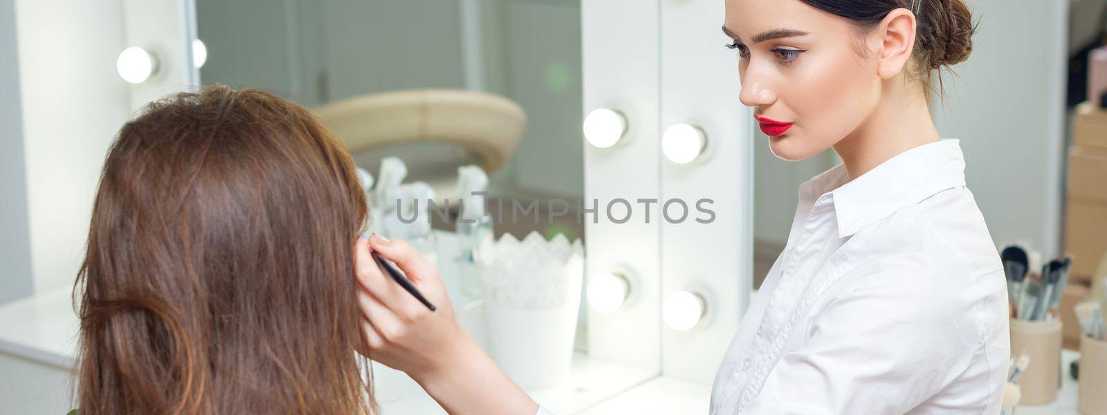 Makeup artist working with client. by okskukuruza