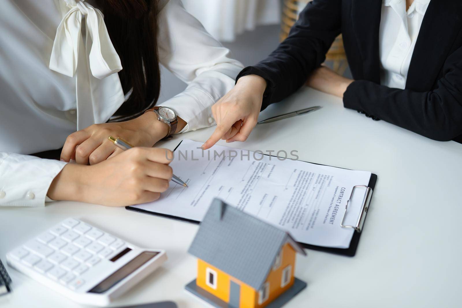 Guarantee, mortgage, agreement, contract, signed, real estate agent pointing to documents for customers to read the agreement before signing important documents.