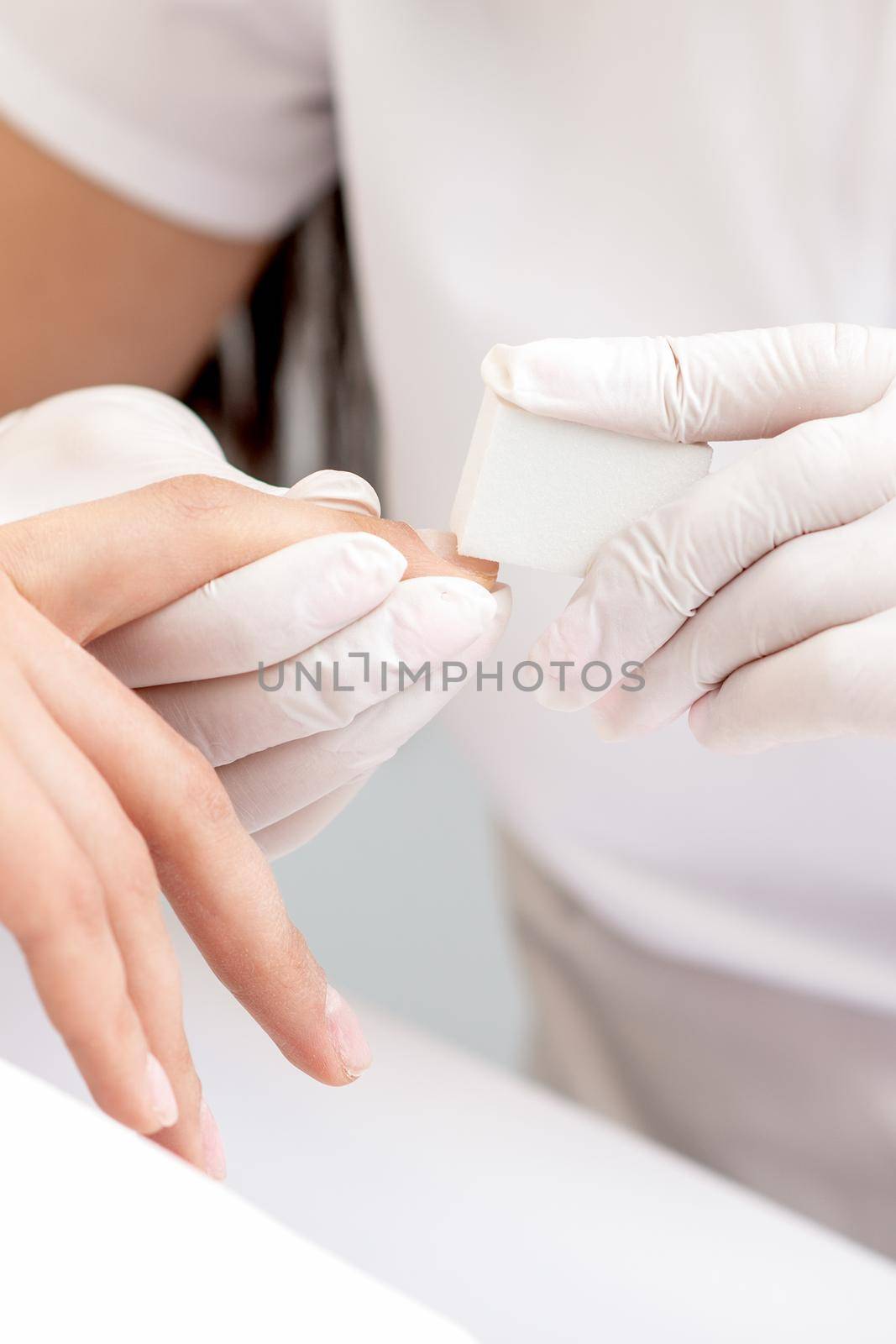 Close up of woman receiving manicure with nail file by manicurist at nail salon