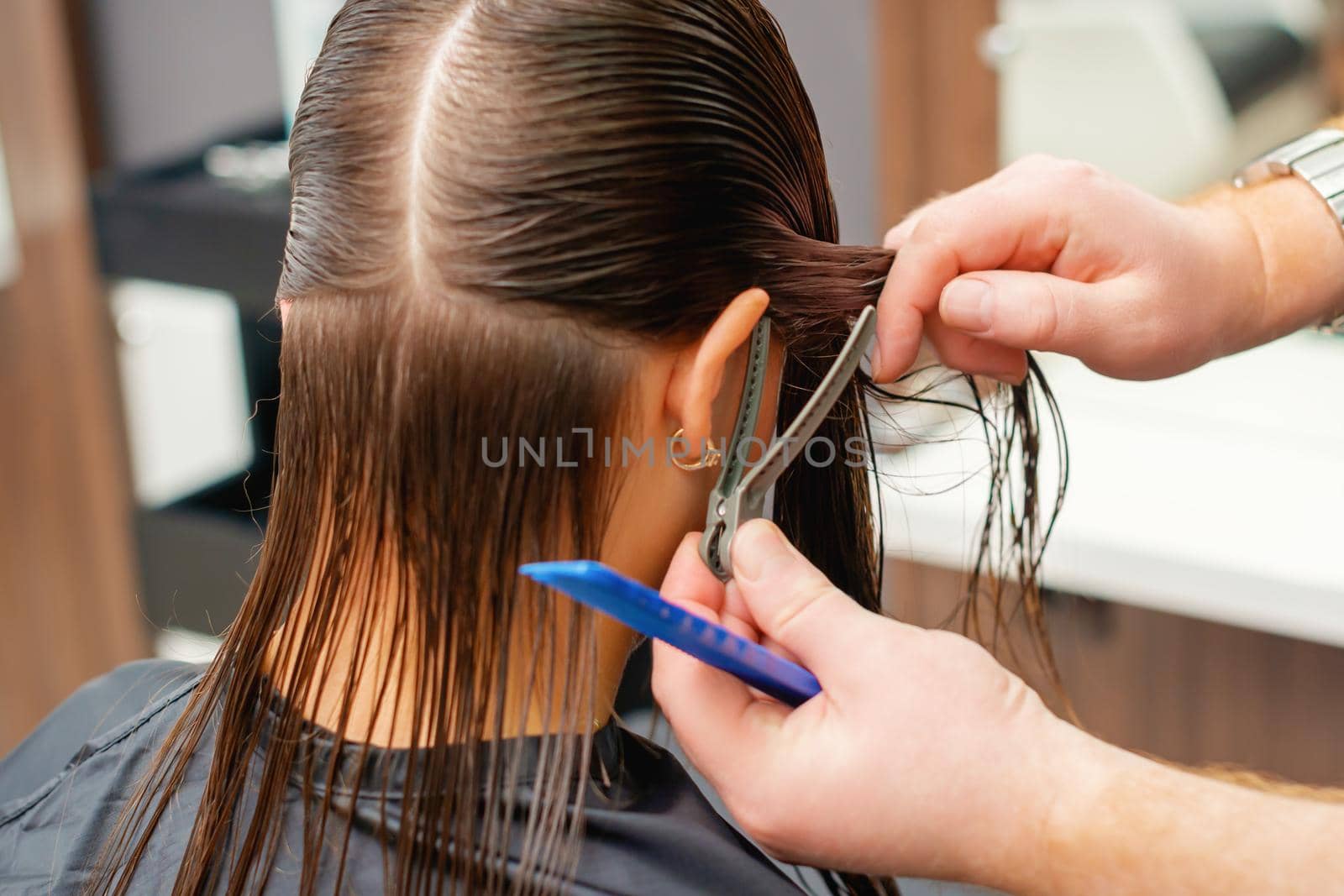 Hands of hairdresser combs hair of young woman in hair salon. Hairstyle process in a beauty salon