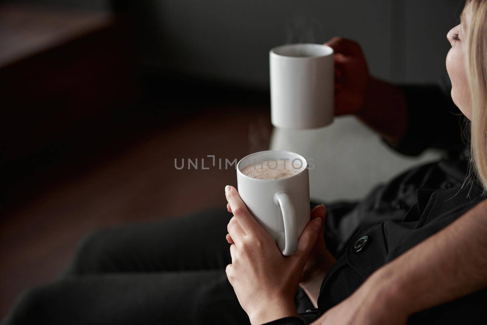 close-up. image of a man and a woman in love with cups of coffee sitting on the sofa.