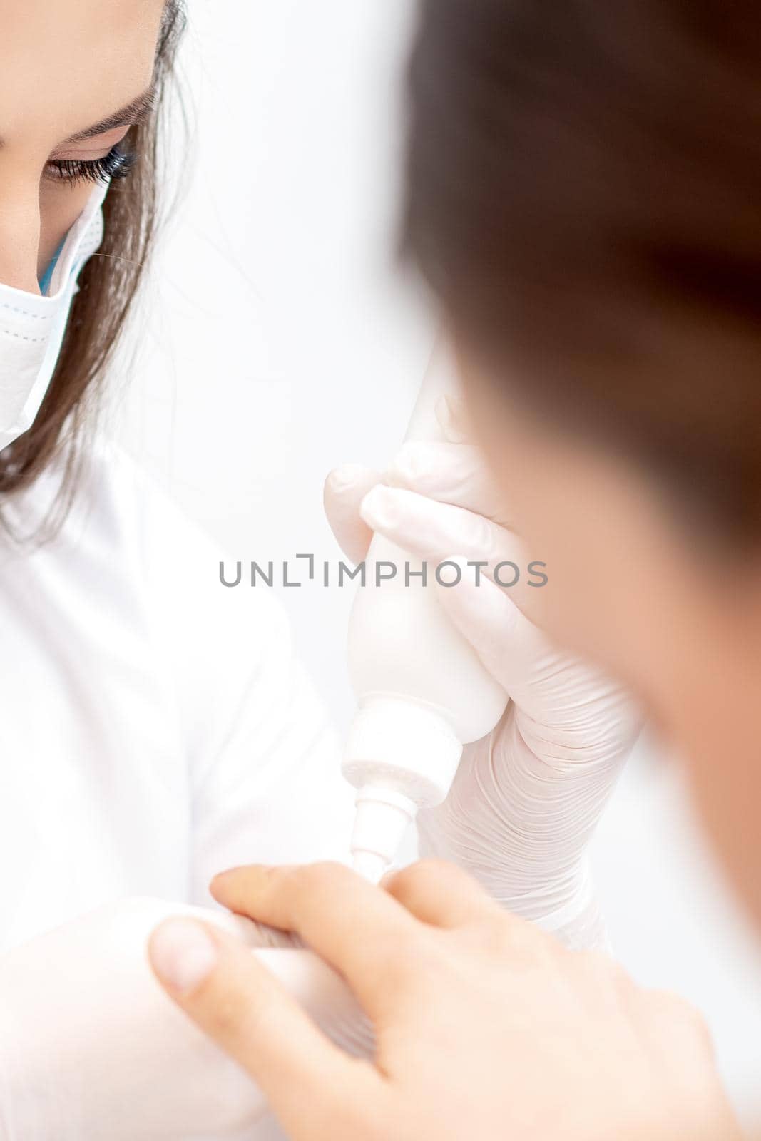 Manicurist pours oil on nails of woman by okskukuruza